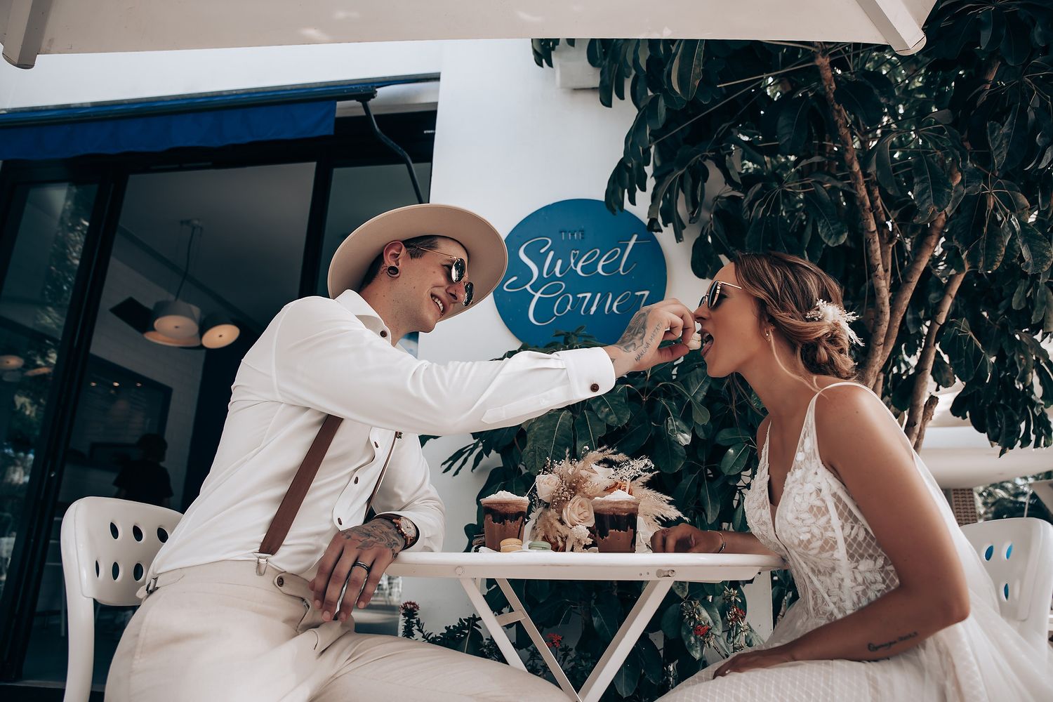 An elegant outdoor wedding reception setup with decorative signage and tropical foliage.