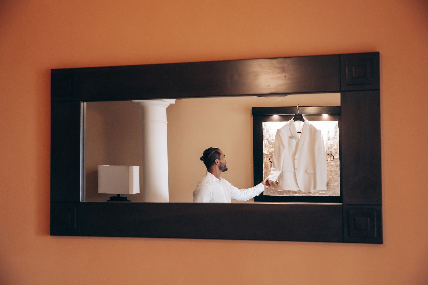 A series of black framed rectangular mirrors mounted on a peach colored wall create a modern minimalist design element.