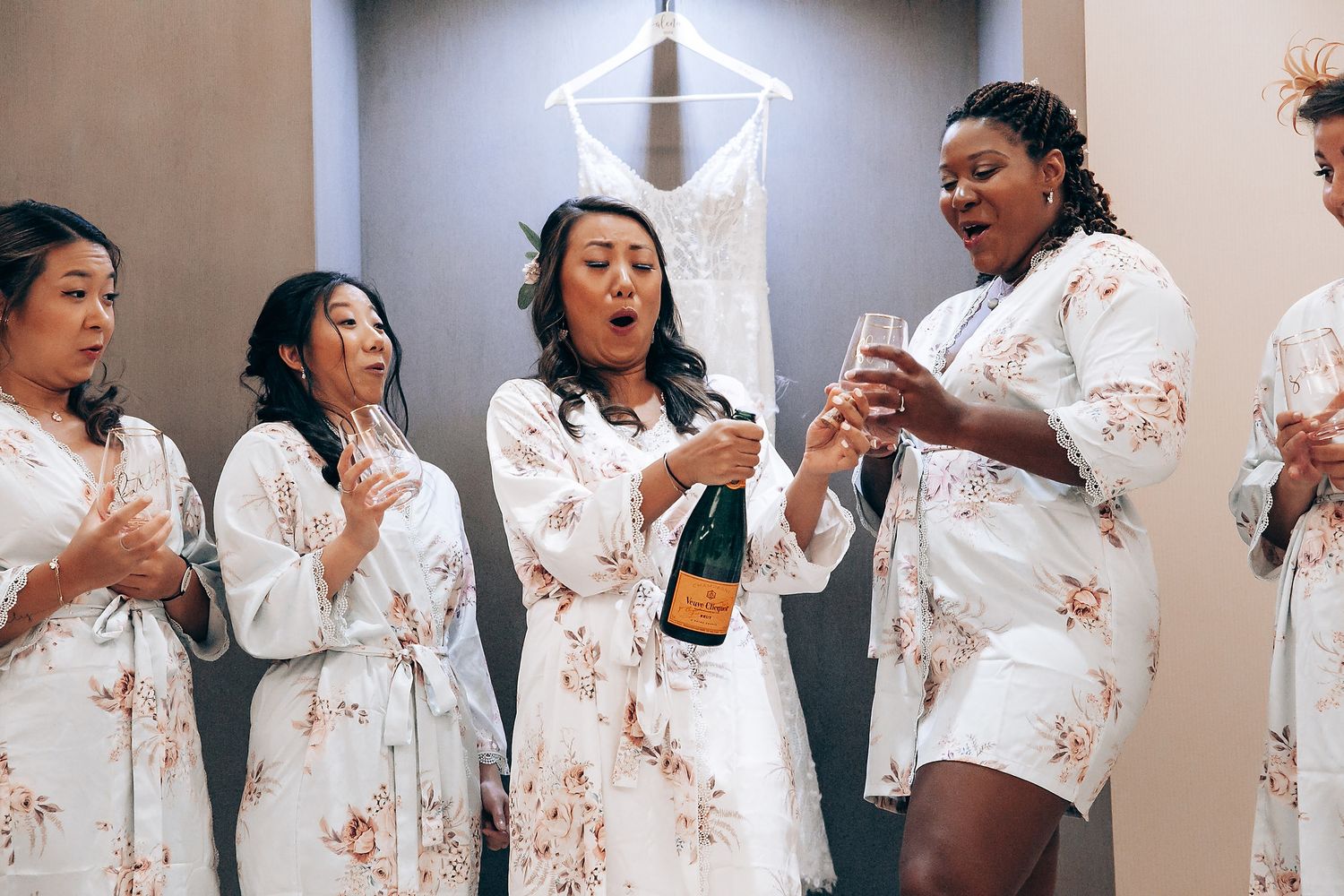 People in coordinated white and pink floral robes posing together against a neutral wall.