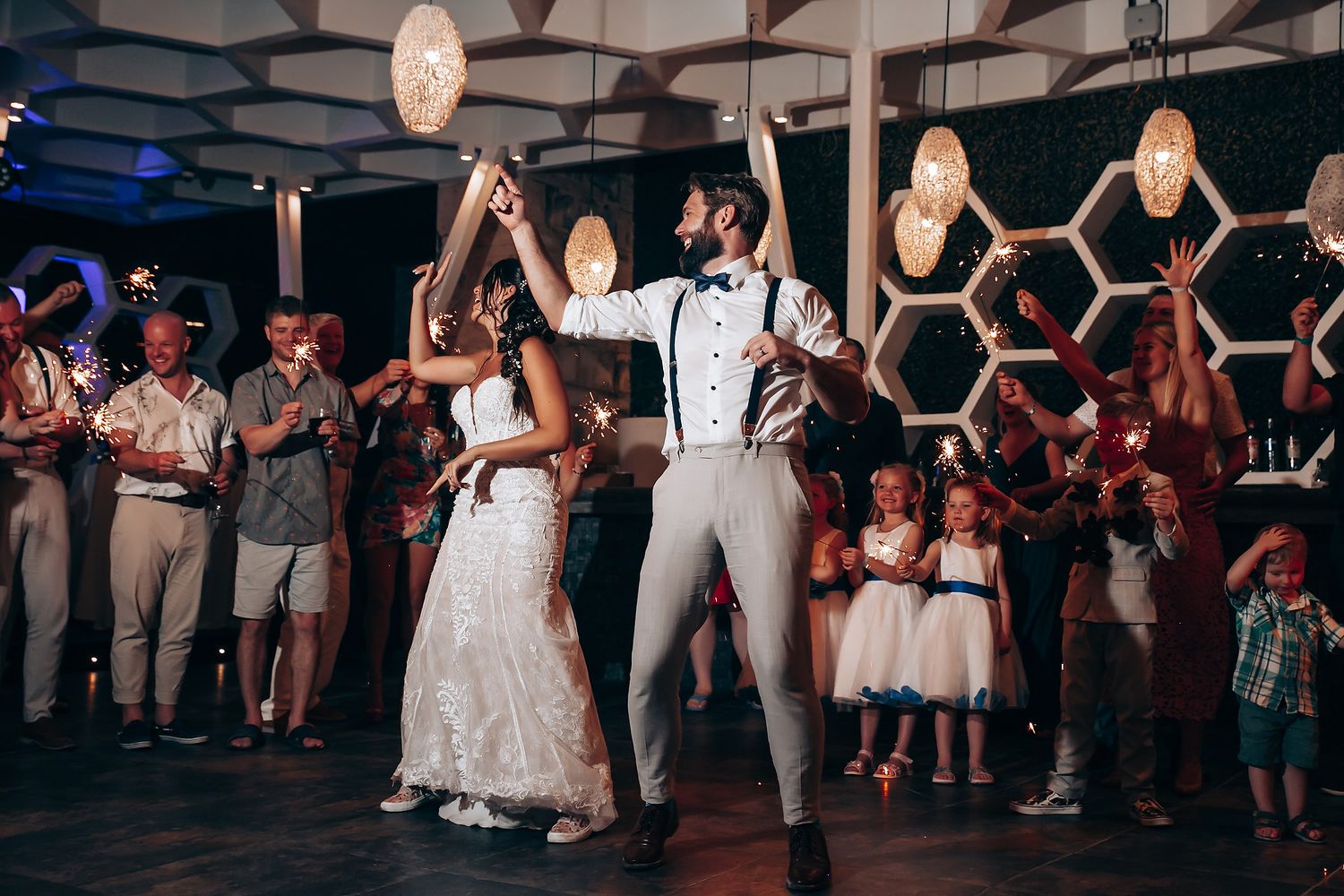 Wedding reception dance floor filled with guests celebrating in a dimly lit venue.