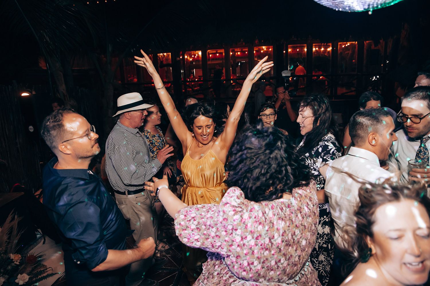 Energetic crowd dancing and celebrating at a nightclub with dramatic lighting and raised hands.
