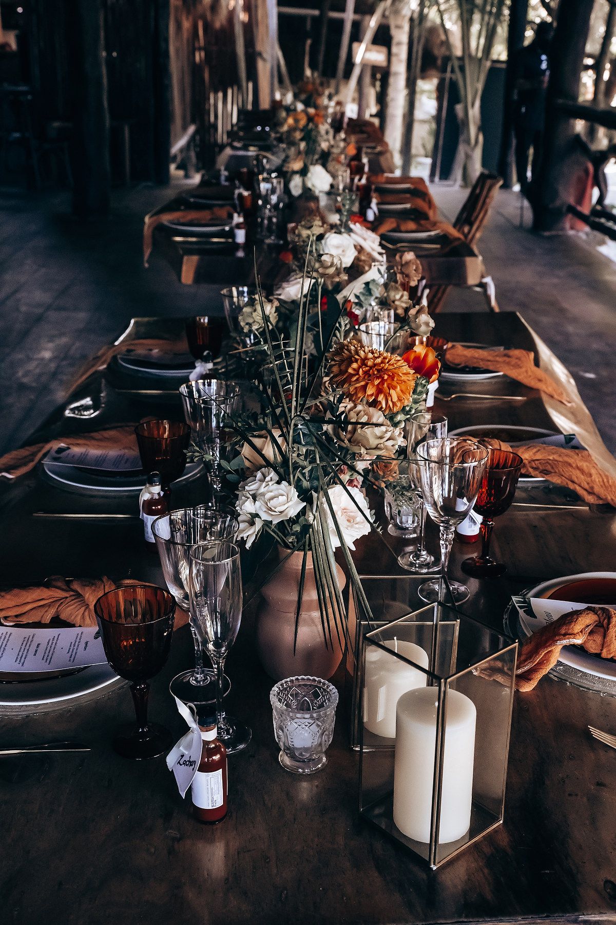 Elegant table setting with dark linens, crystal glasses and candlelight at a formal wedding reception.