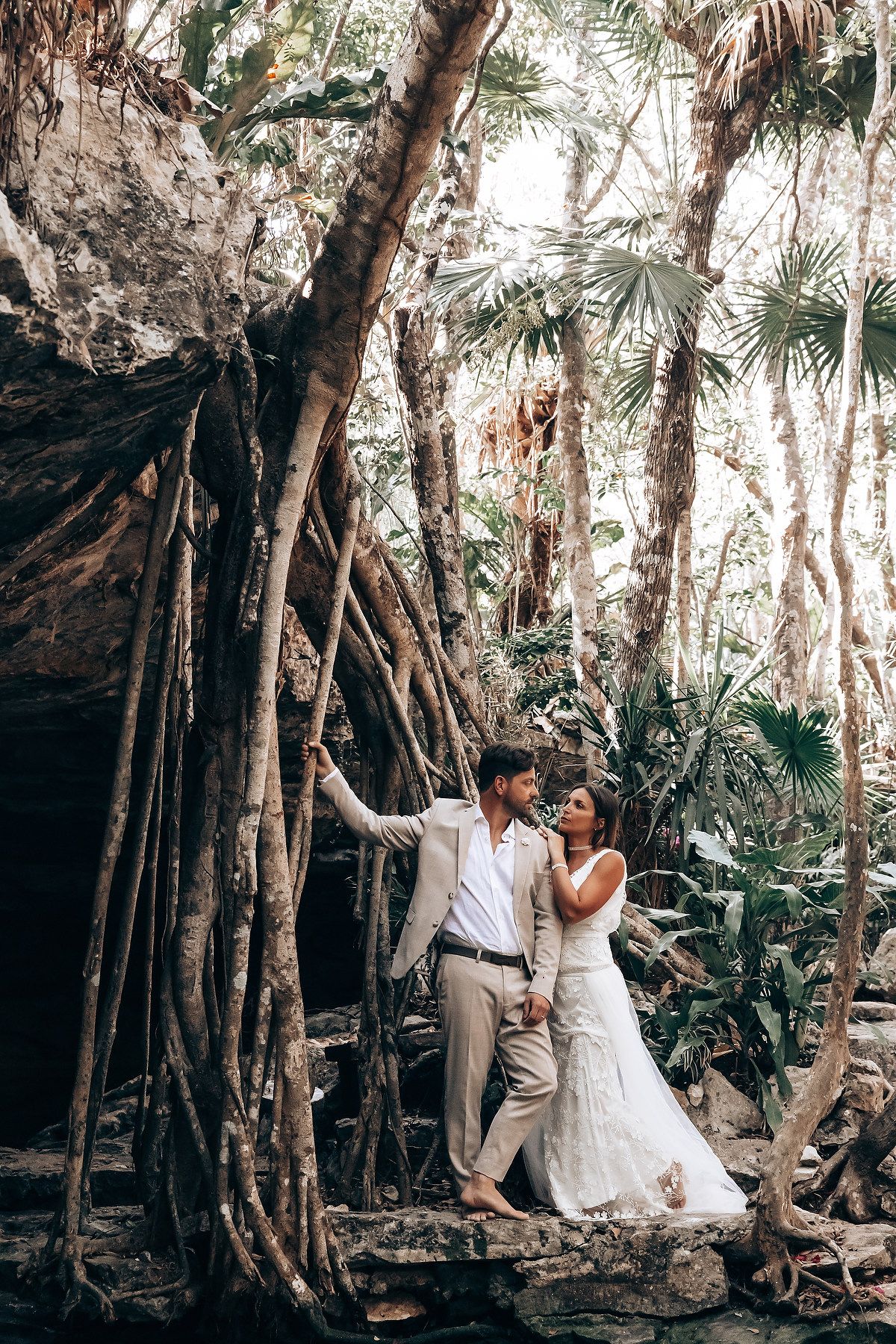 Romantic wedding photos taken in a natural forest setting with tropical vegetation.