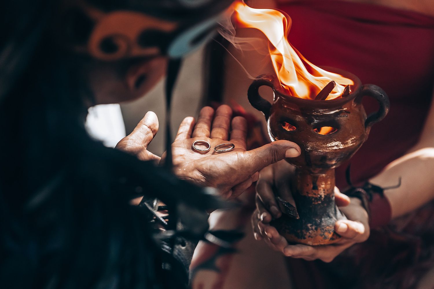 Hands hold ceremonial candles creating a warm glow in the darkness.