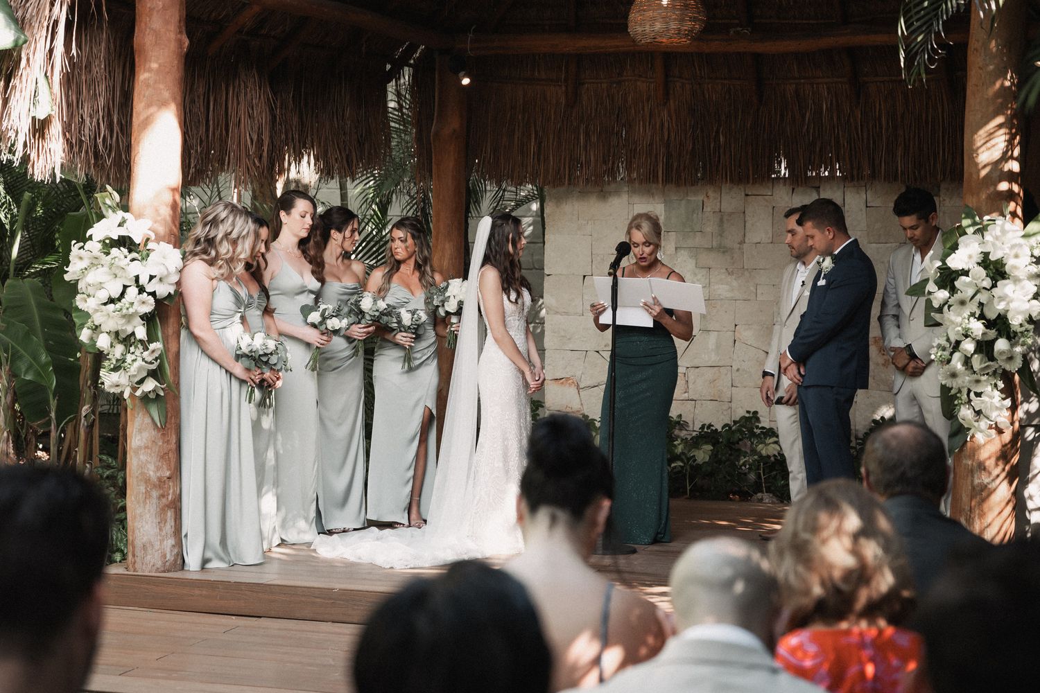 Bride and groom exchange vows at tropical outdoor wedding ceremony with bridesmaids.