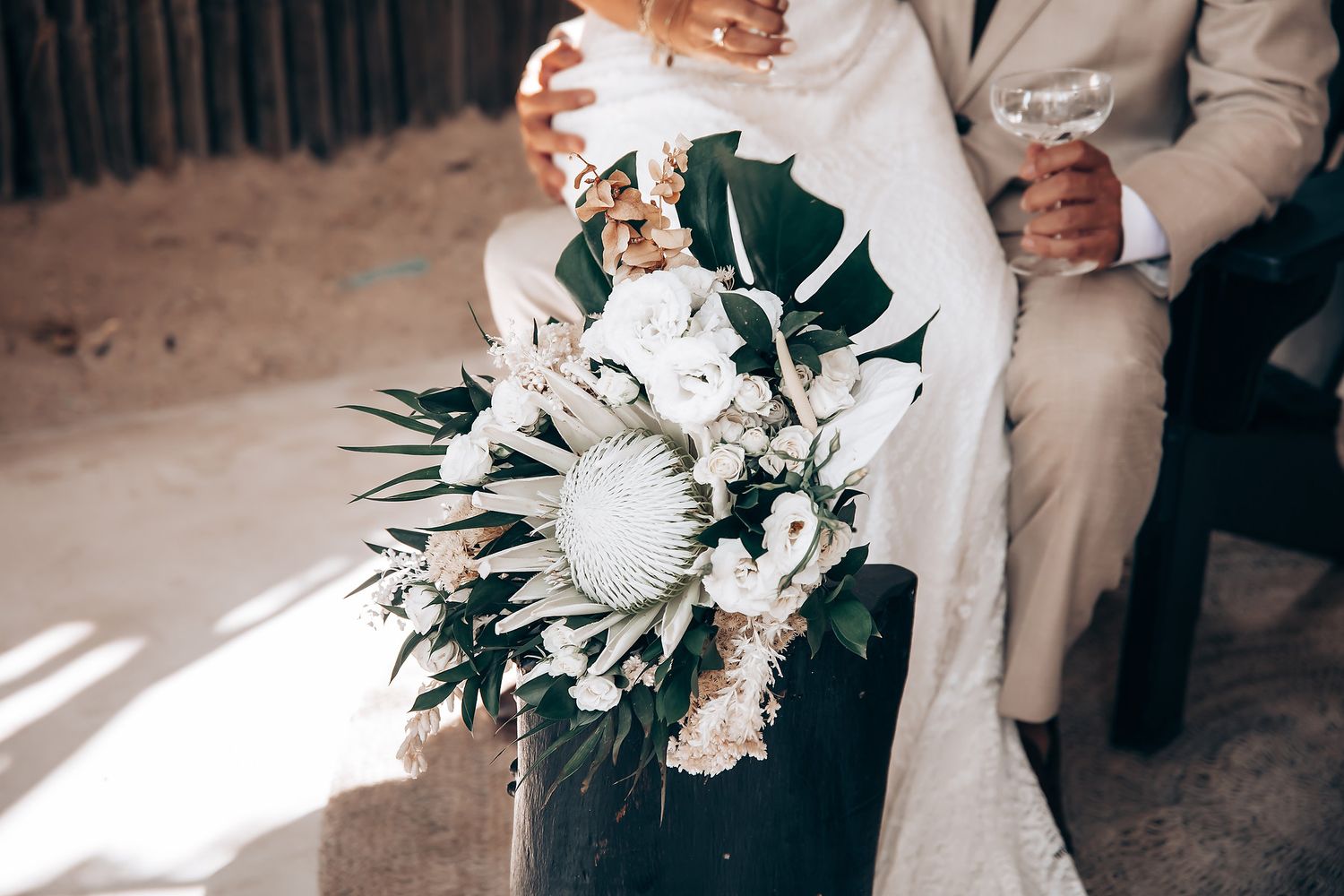 Elegant wedding couple embracing in a bright indoor setting with white floral arrangements.