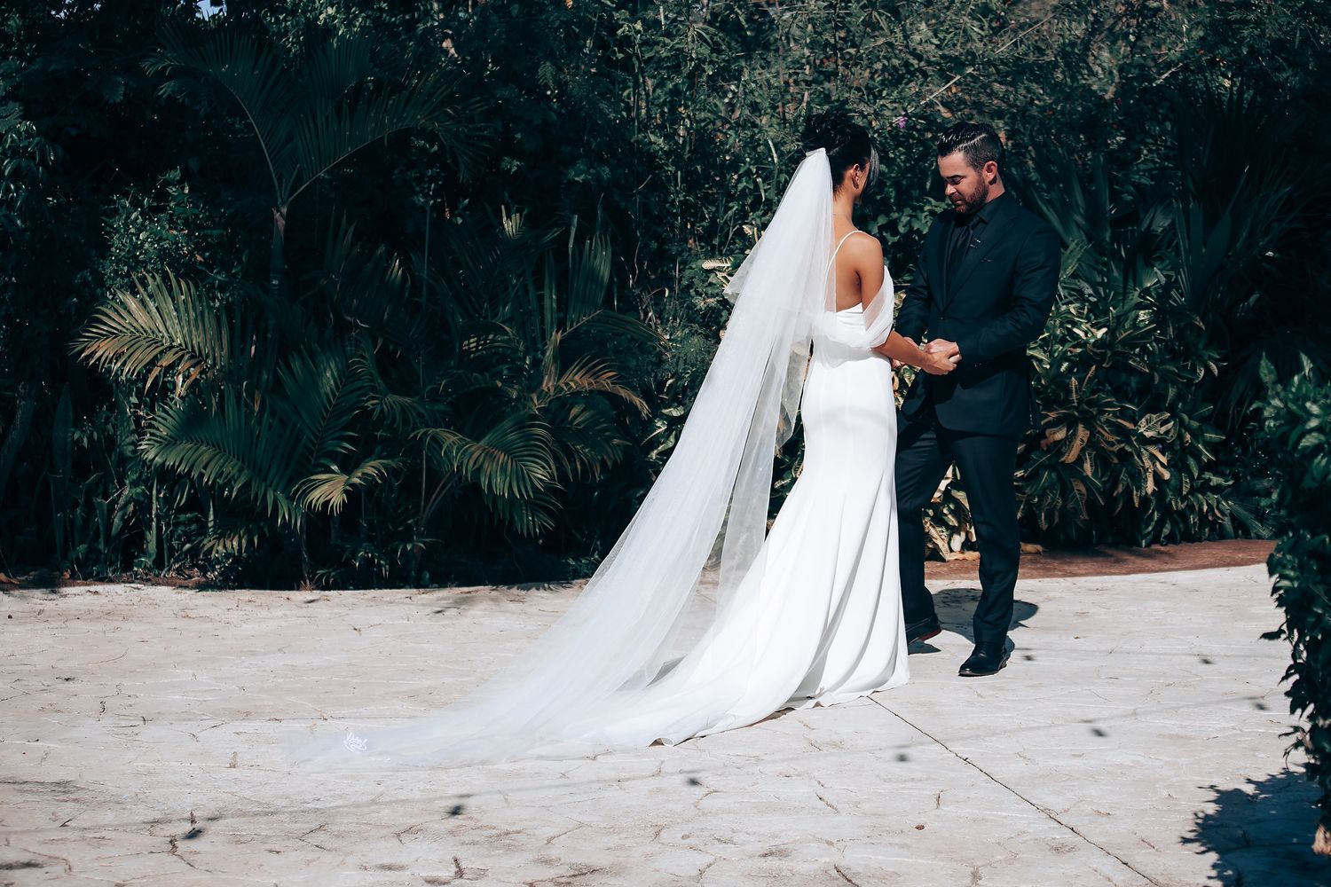A wedding couple having their first look moment outdoors on a garden path.