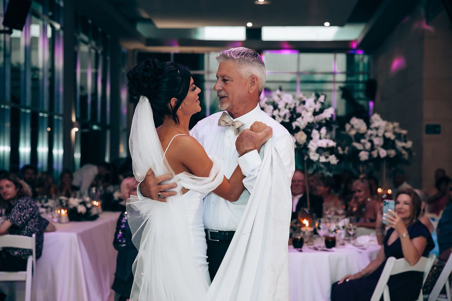 Wedding reception dance floor with purple ambient lighting and guests dancing.