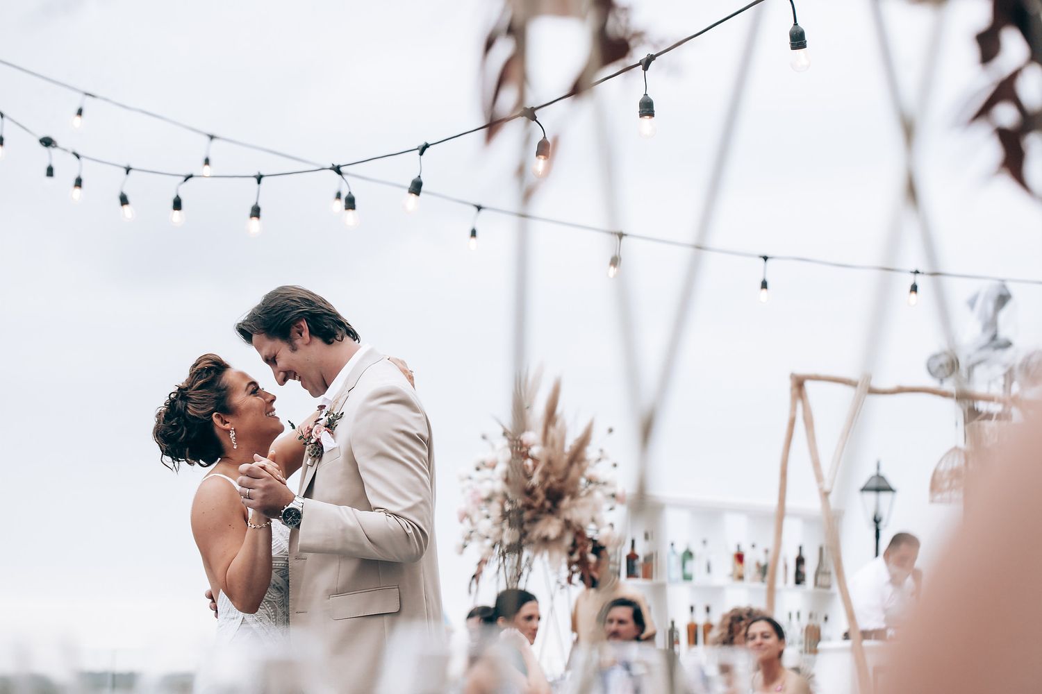 Outdoor wedding reception area decorated with hanging string lights and natural elements.