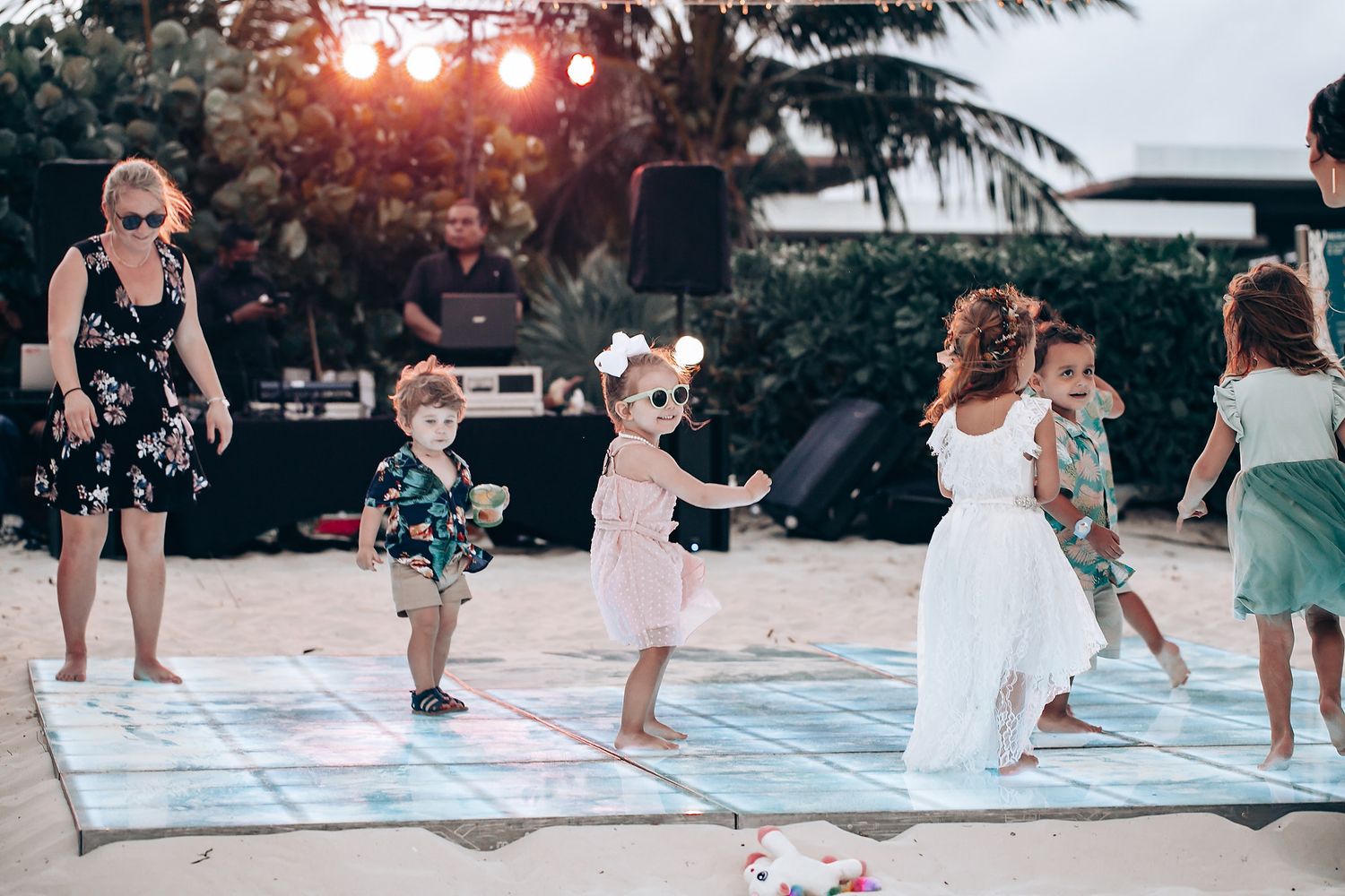Group performs coordinated dance routine at sunset on an outdoor patio near palm trees.