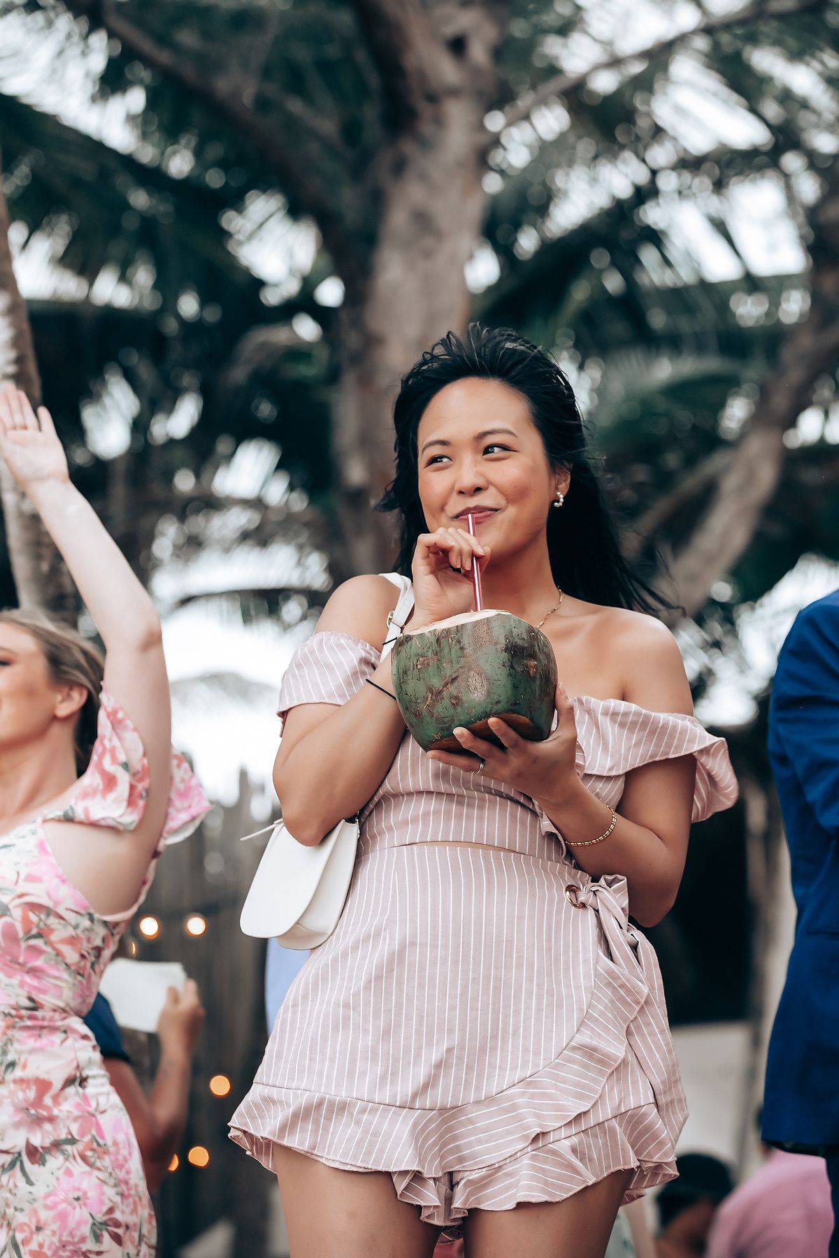 Guest enjoying fresh coconut drinks at a tropical beach celebration.