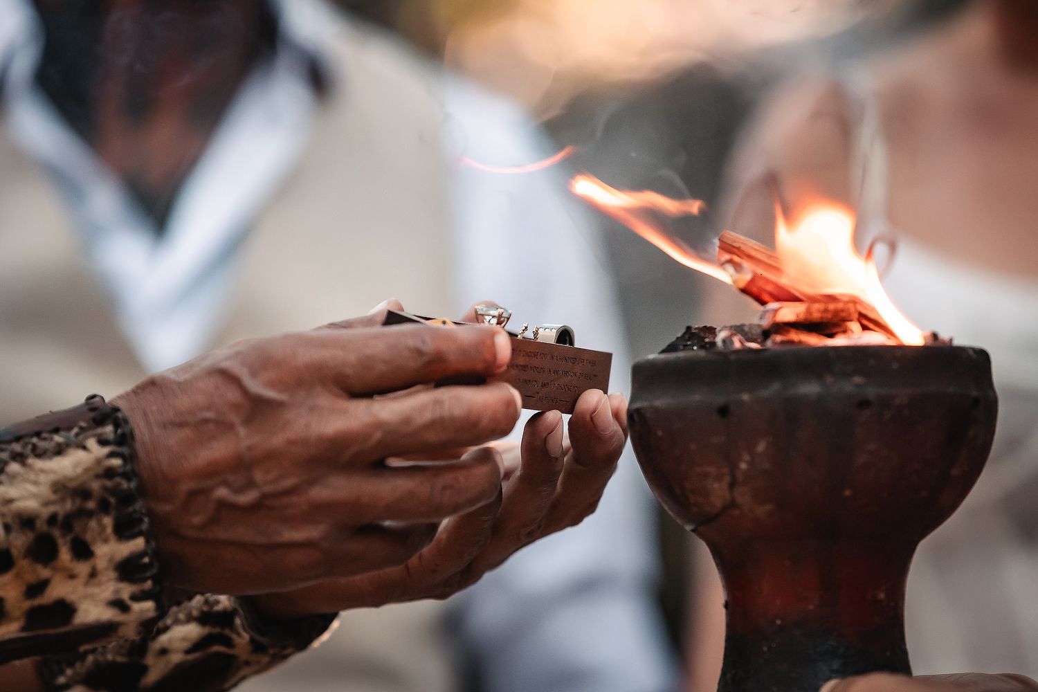 Close-up shot of hands lighting ceremonial incense during a traditional ritual.
