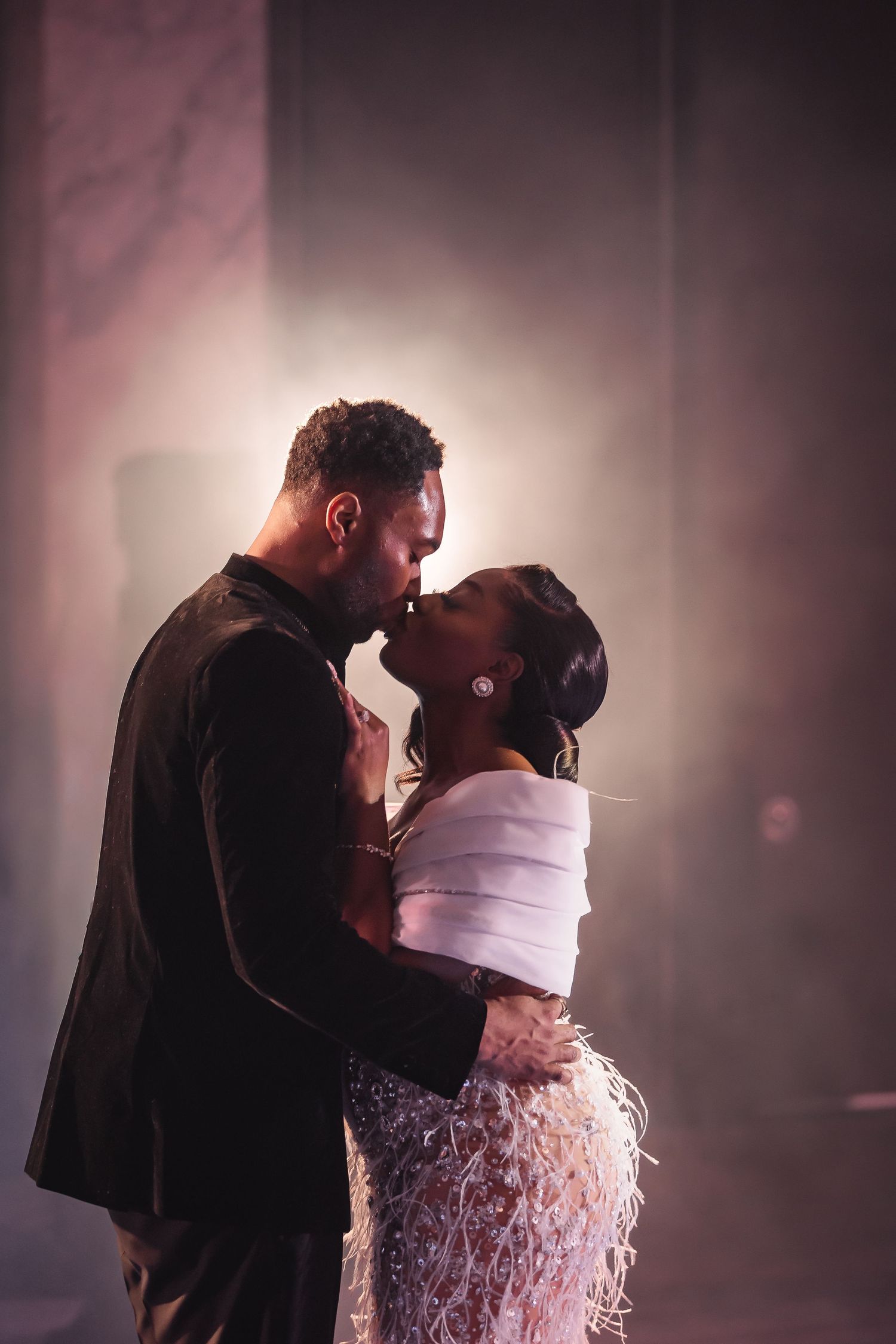 Intimate wedding dance moment captured in dramatic lighting with soft focus background.