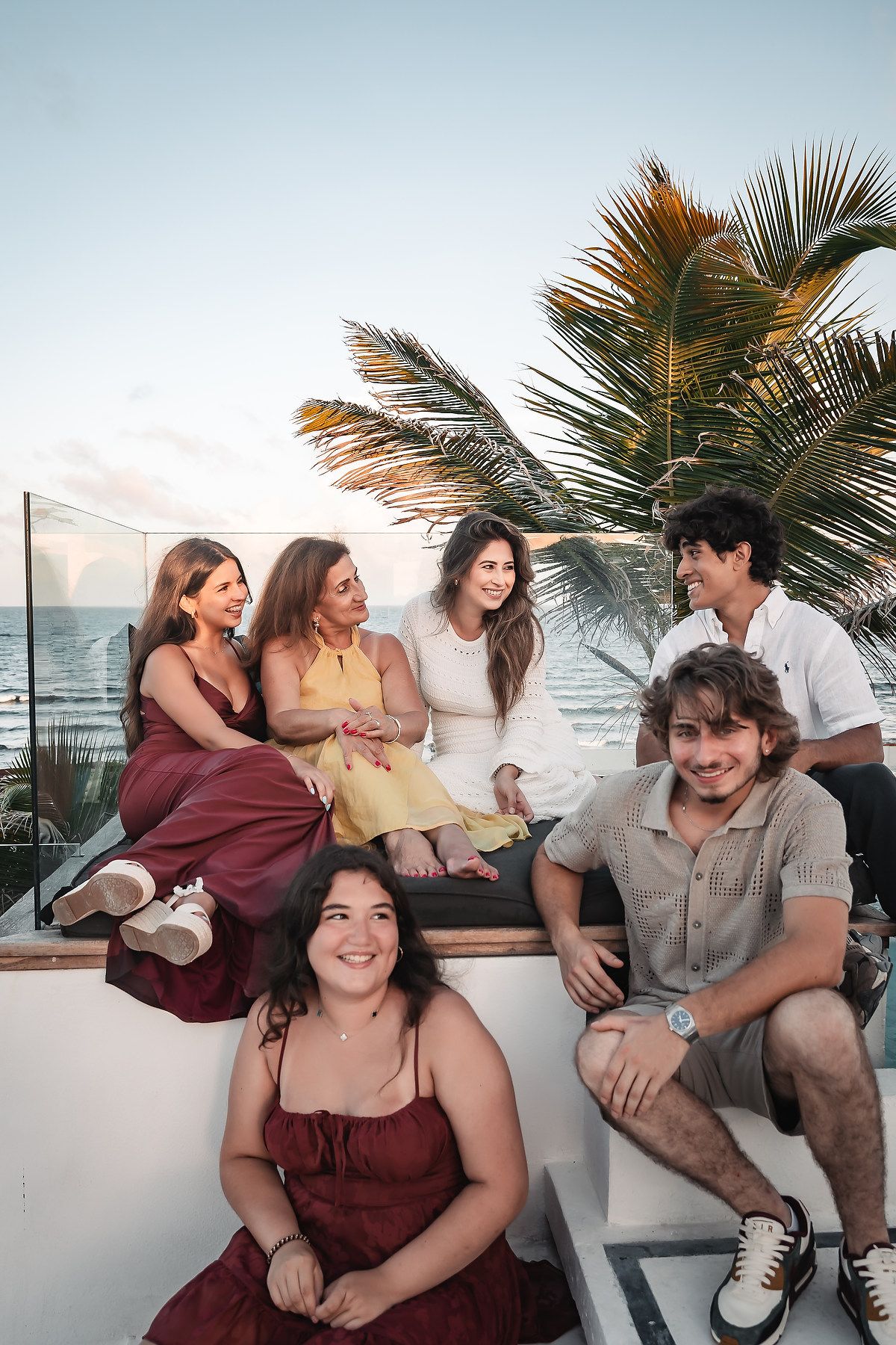 Friends enjoying a relaxed moment together on a coastal wall with tropical scenery.