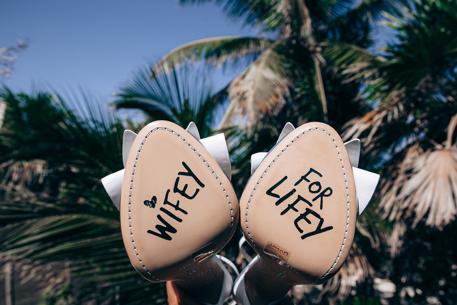 Two heart-shaped decorations with text displayed against tropical palm trees in the background.