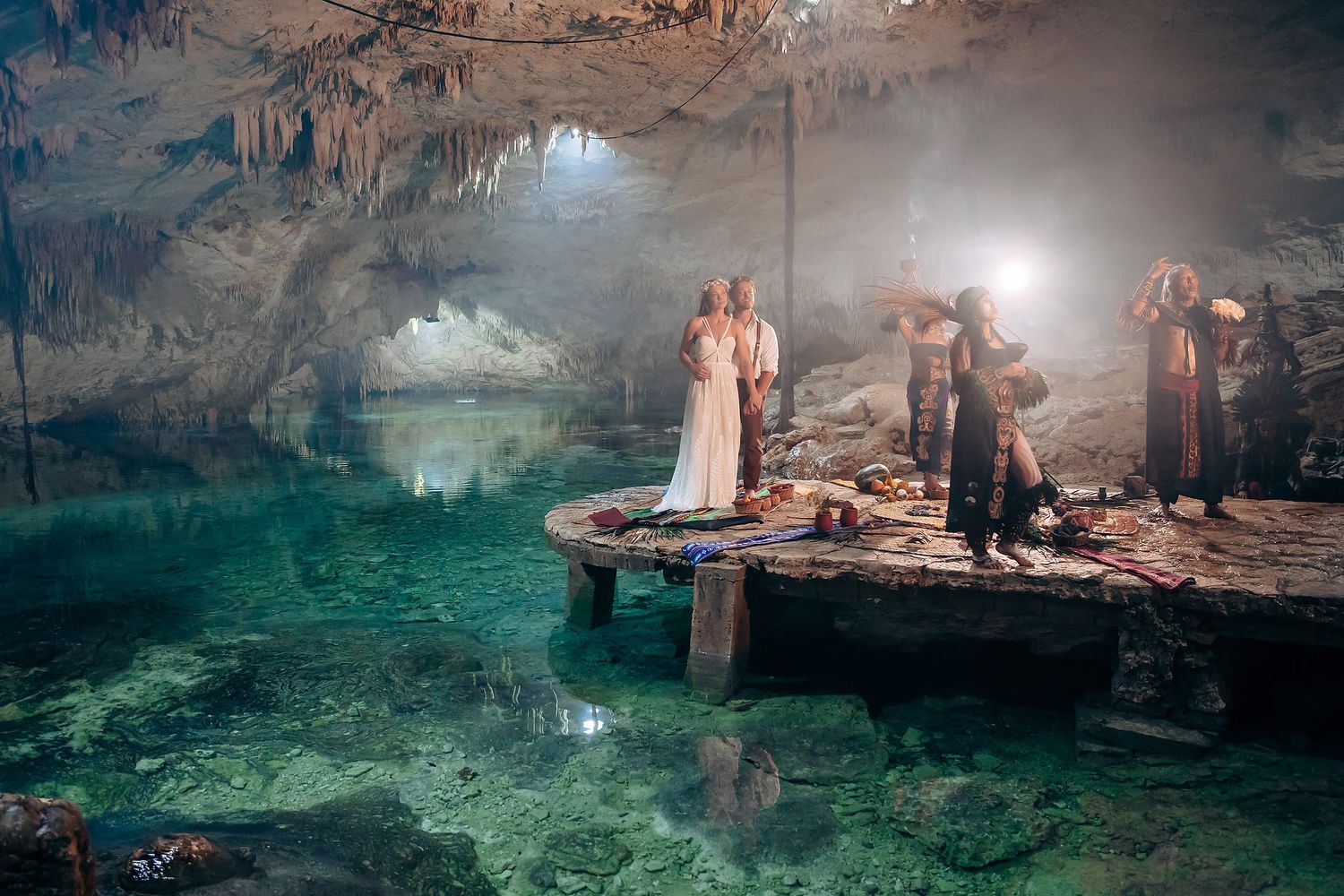 Turquoise waters illuminate a mystical cenote cave with natural rock formations and swimmers.