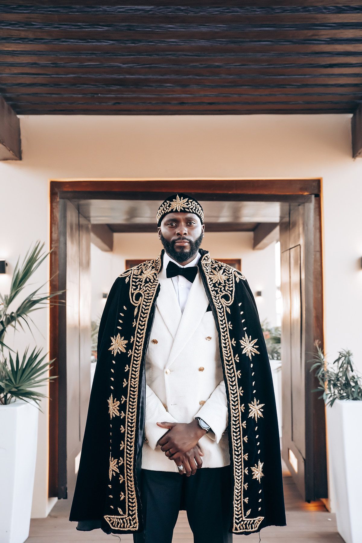 Elegant groom wearing an embroidered black and gold ceremonial jacket with white dress shirt.
