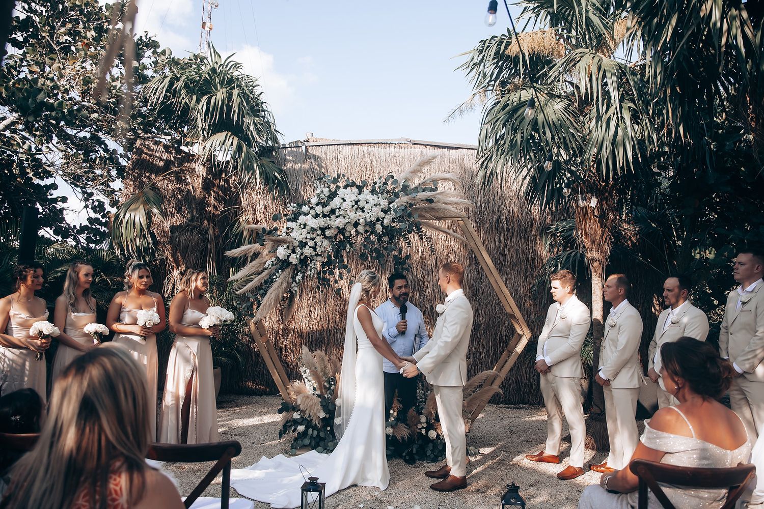 Wedding ceremony setup with tropical palm trees and natural decor elements.