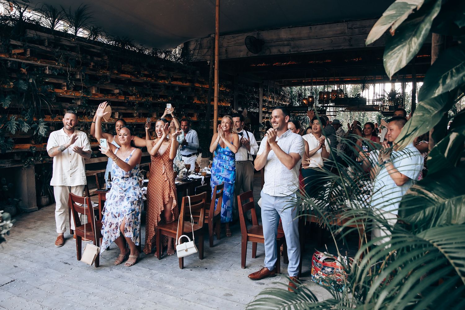 People gather in an outdoor market setting with tables and chairs arranged under covered walkways.