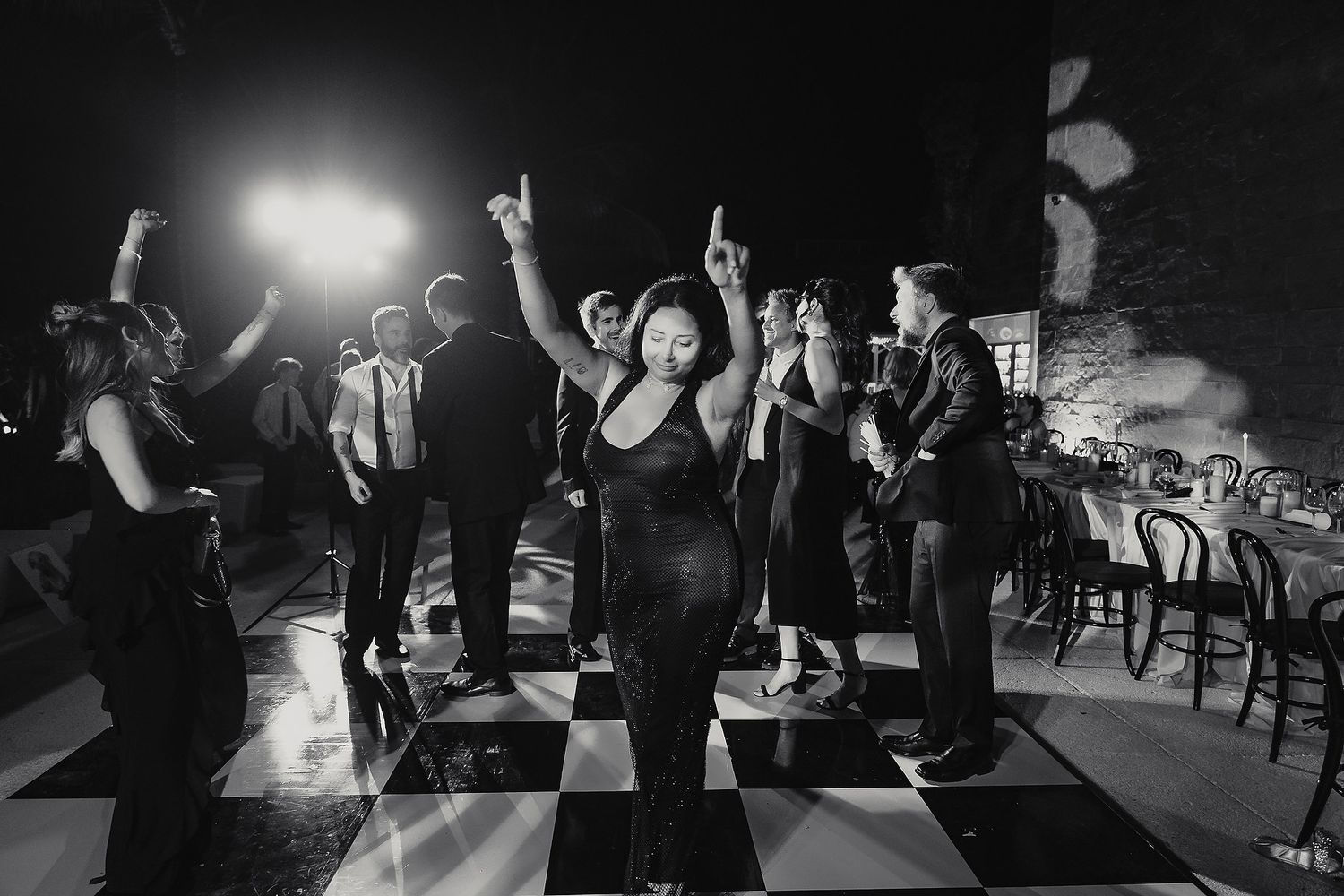 People dancing and celebrating at a lively nightclub party with dramatic lighting and silhouettes.