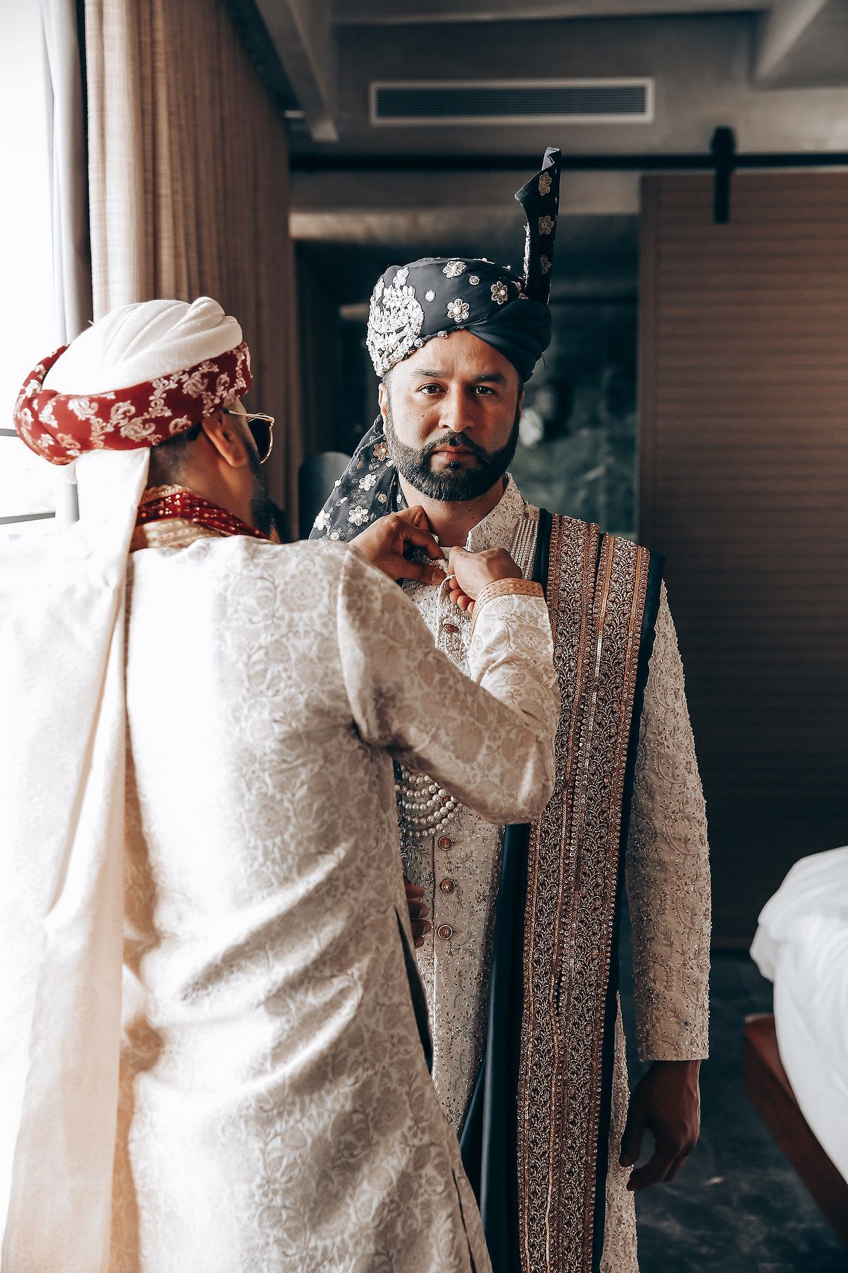 A person in traditional Indian wedding attire adjusts their outfit before the ceremony.