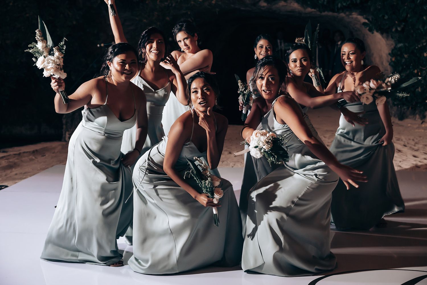 Bridesmaids in silver dresses dancing together at a wedding reception.