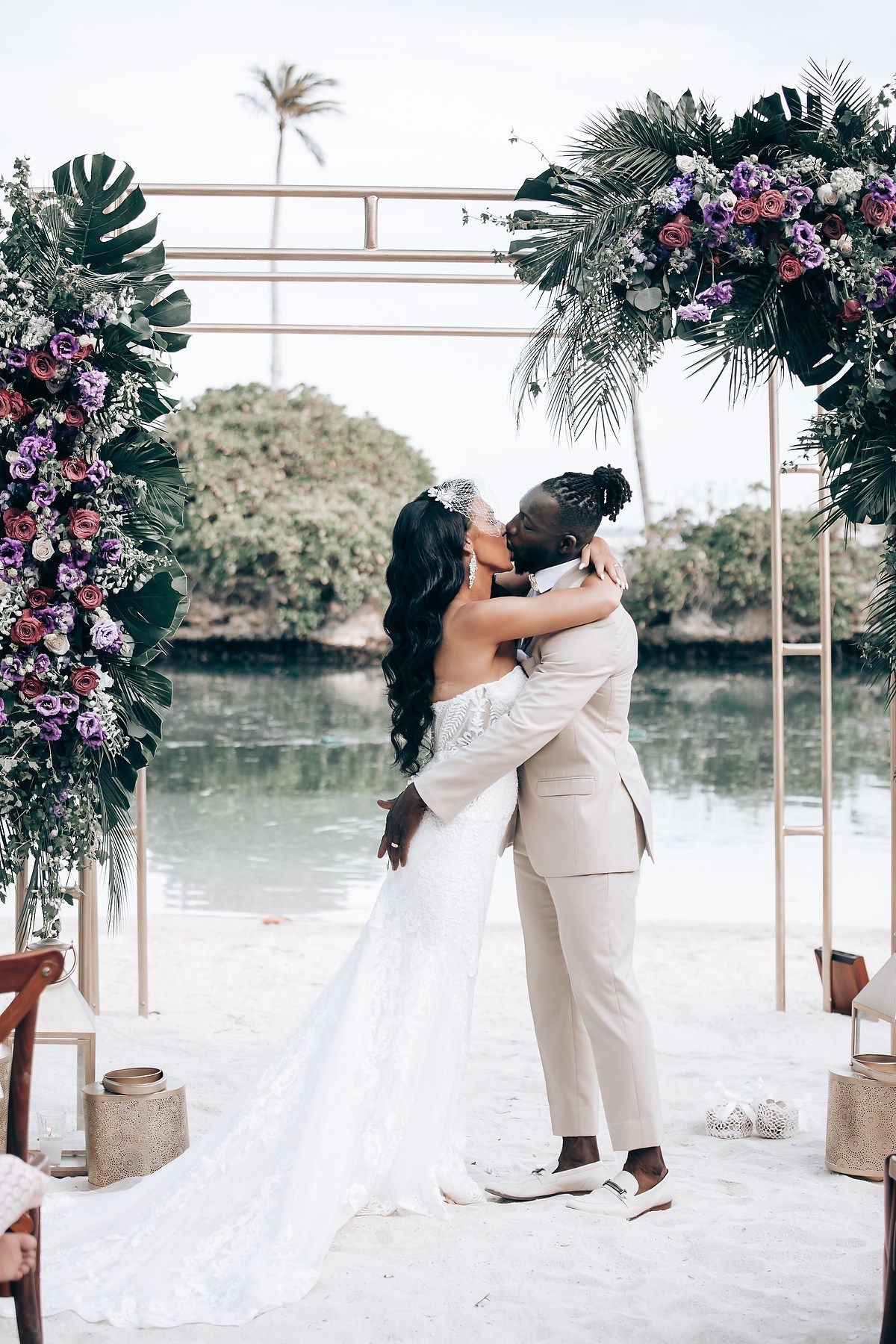 Romantic beach wedding ceremony setup with tropical floral arrangements and white canopy.