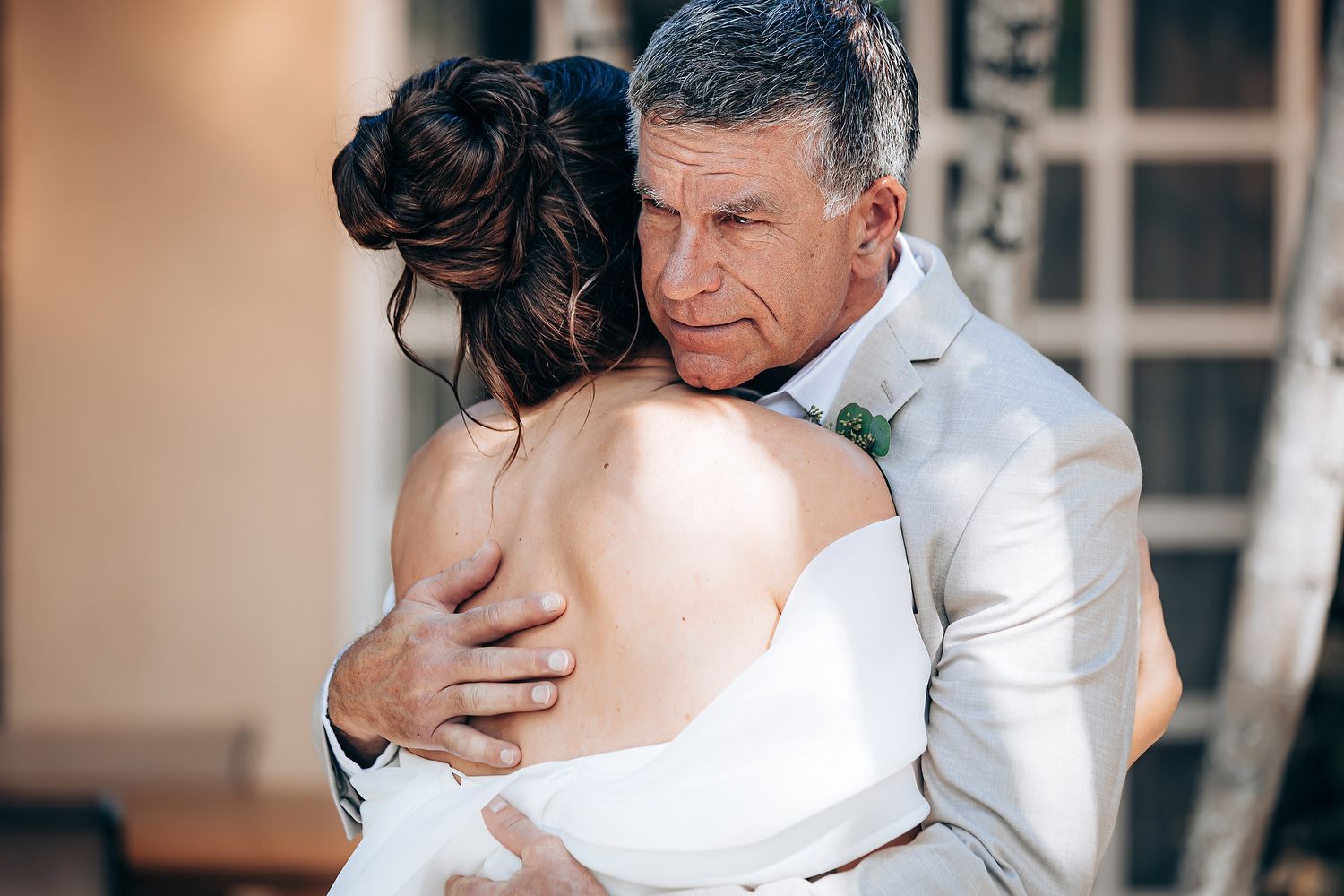 Emotional embrace between people in formal wedding attire at an indoor venue.