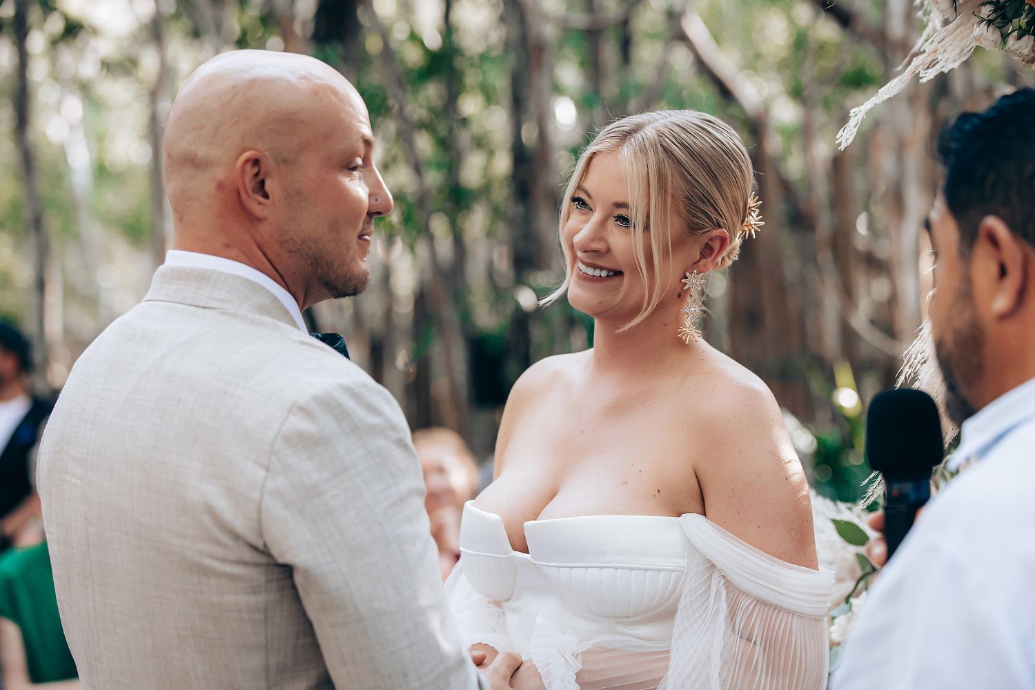 Wedding guests dance and celebrate together during an outdoor reception in a wooded setting.