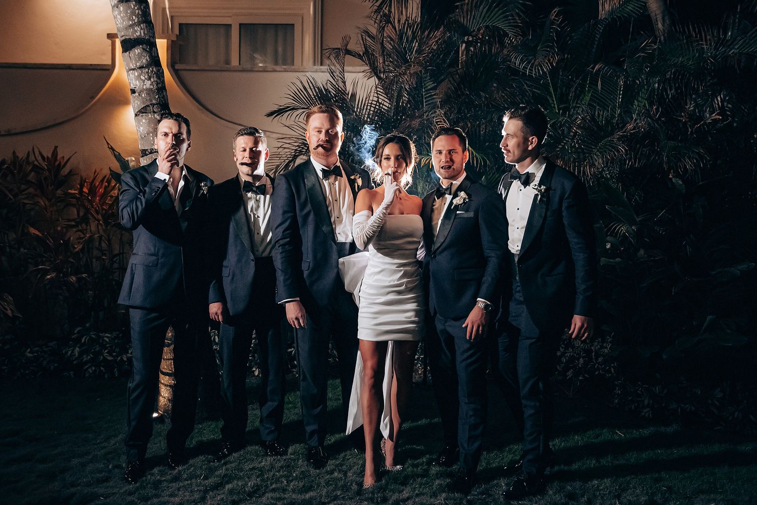 Wedding party poses for creative nighttime portrait with mixed lighting.