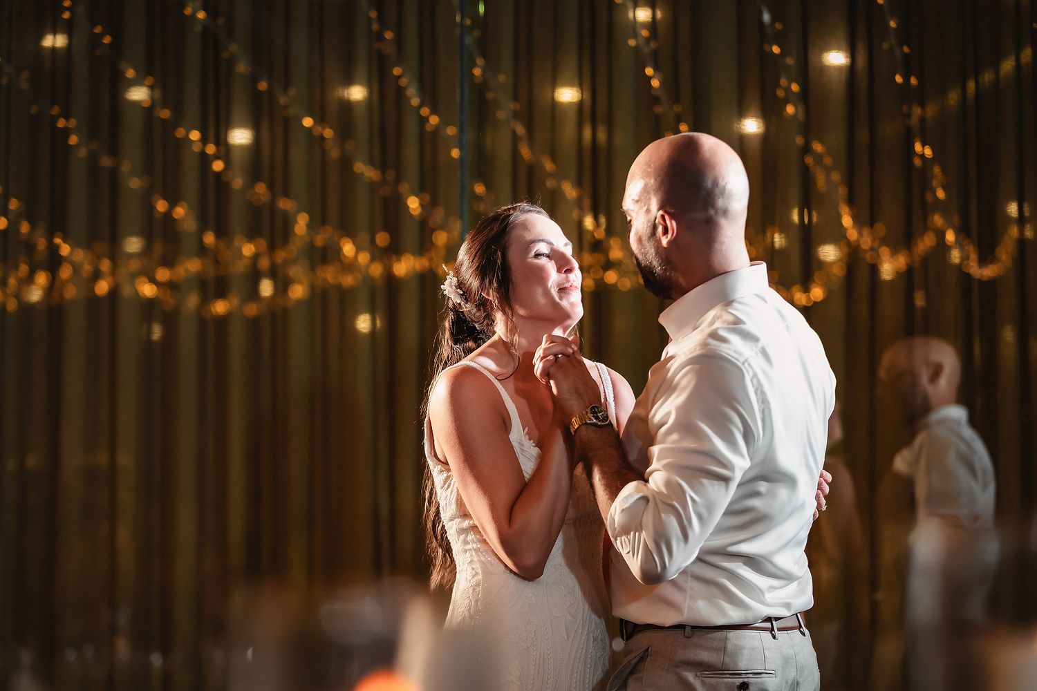 Joyful dance moment captured under glowing string lights at wedding reception.