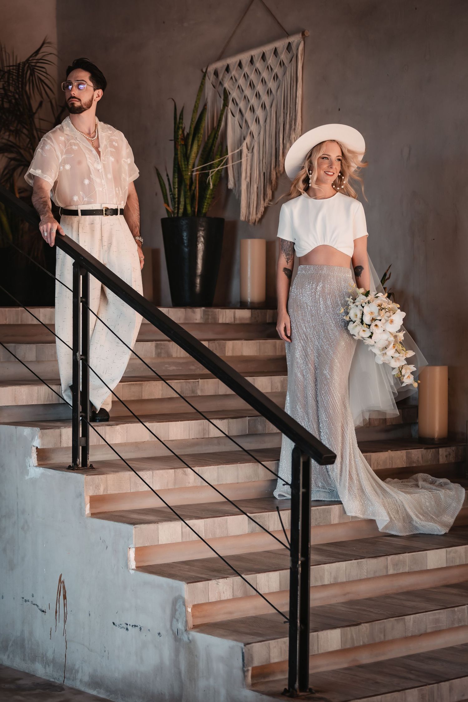 Wedding couple ascending modern concrete stairs with black railings.