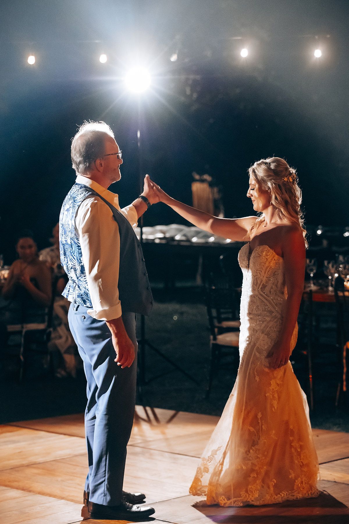 Wedding couple sharing their first dance under spotlights at nighttime reception.
