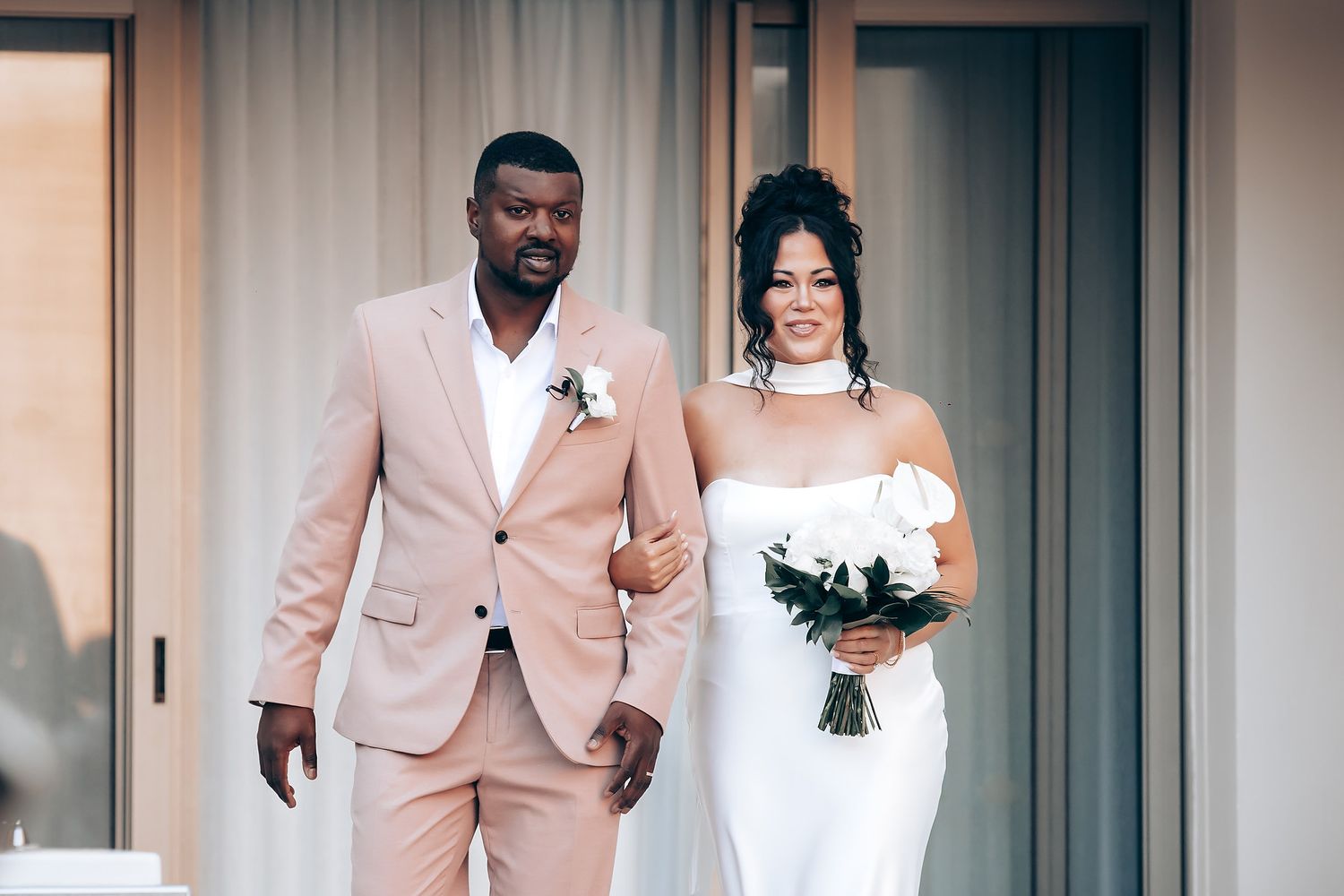 Wedding couple shares intimate moment in front of modern interior setting.