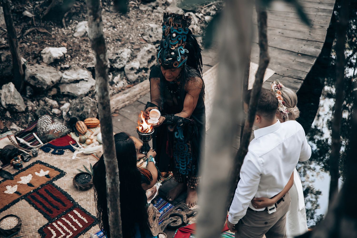 Rustic woodland ceremony space with decorative rugs and natural stone backdrop.
