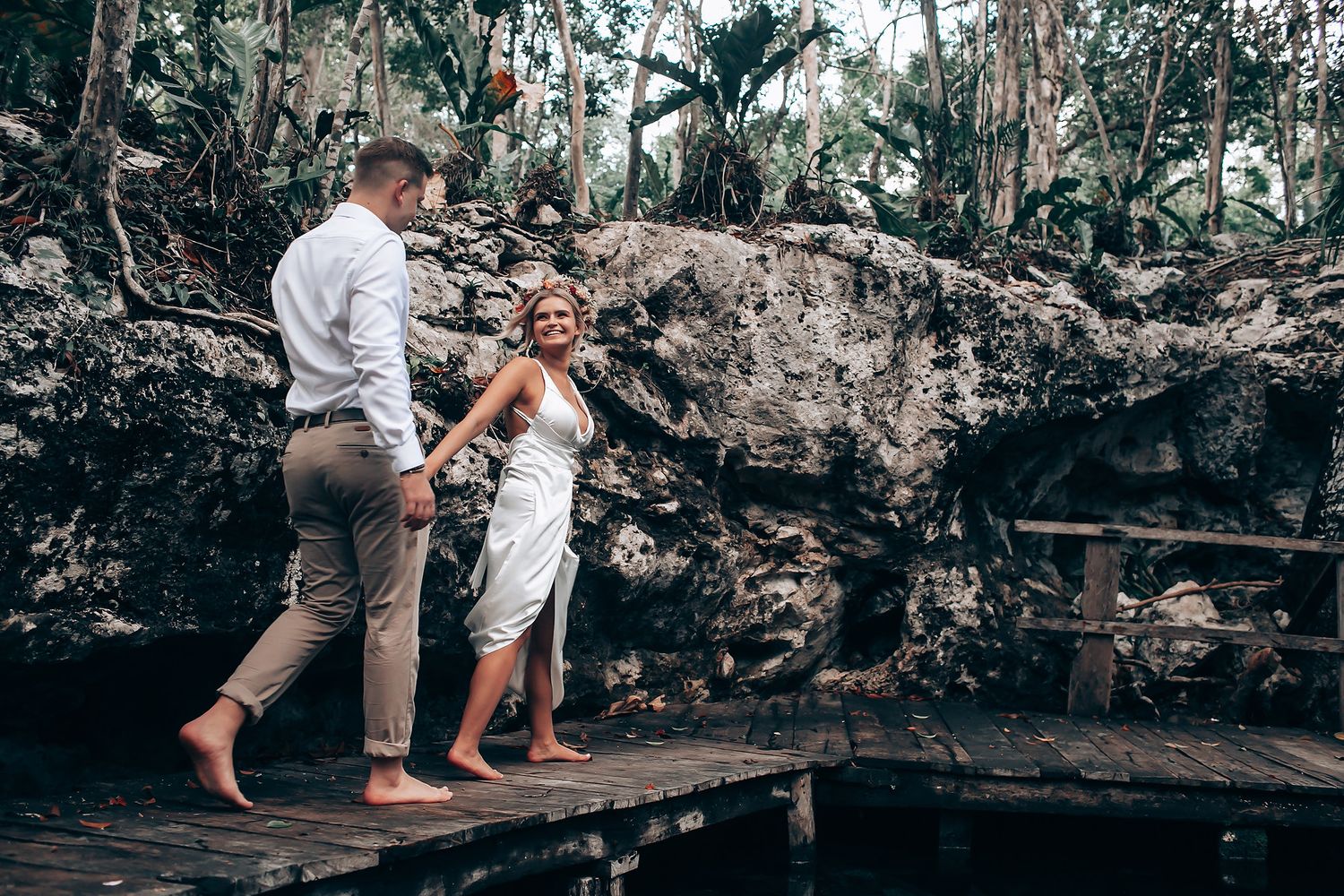 A romantic moment captured on a wooden platform surrounded by lush jungle and rock formations.