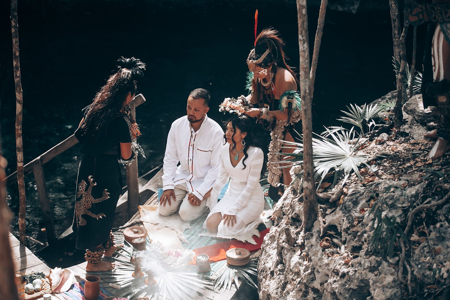 A traditional outdoor wedding ceremony takes place in a lush forest setting with guests gathered around.