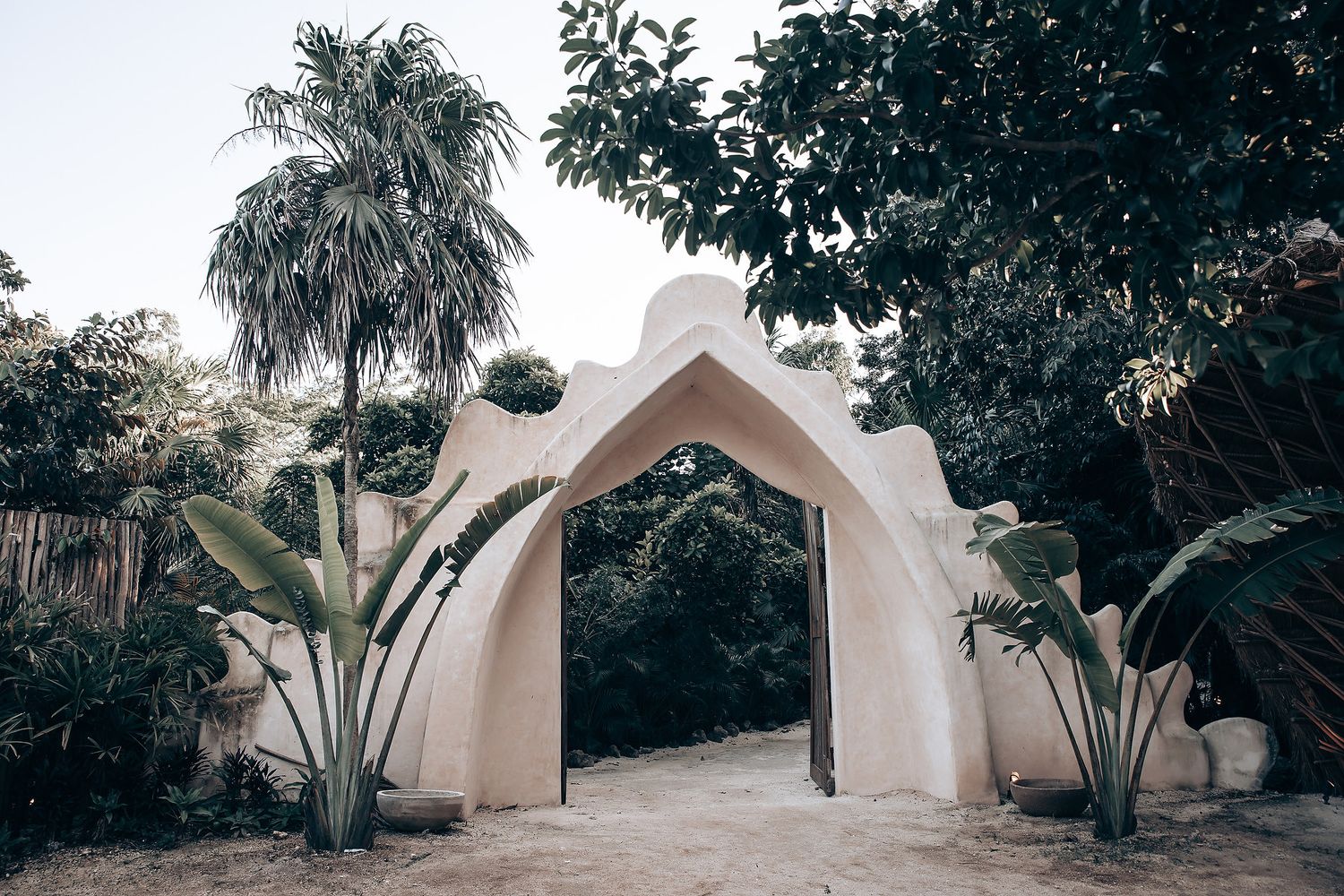 A series of modern dome-shaped structures nestled among tropical palm trees and lush greenery in a peaceful garden setting.