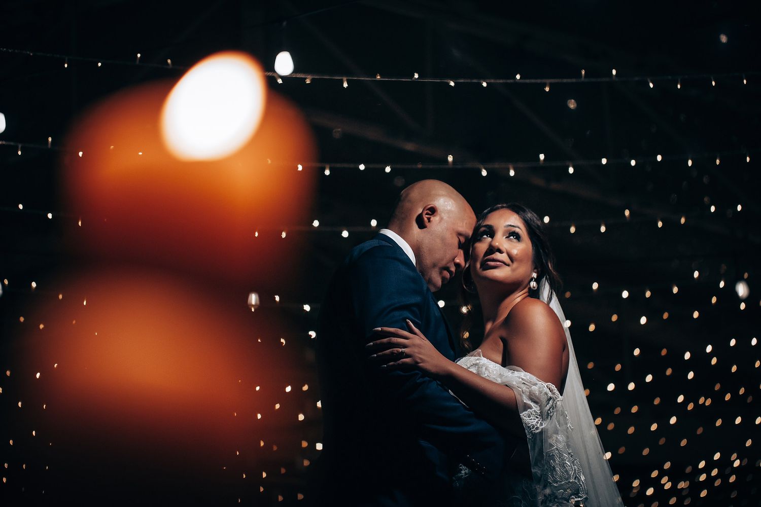 A romantic first dance moment under twinkling string lights at an evening wedding reception.