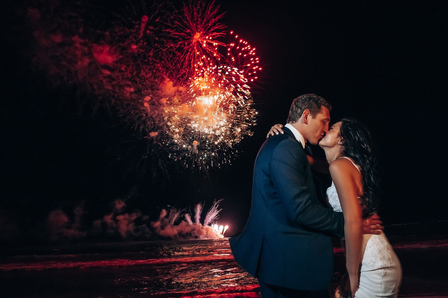 Romantic wedding moment with fireworks lighting up the night sky.