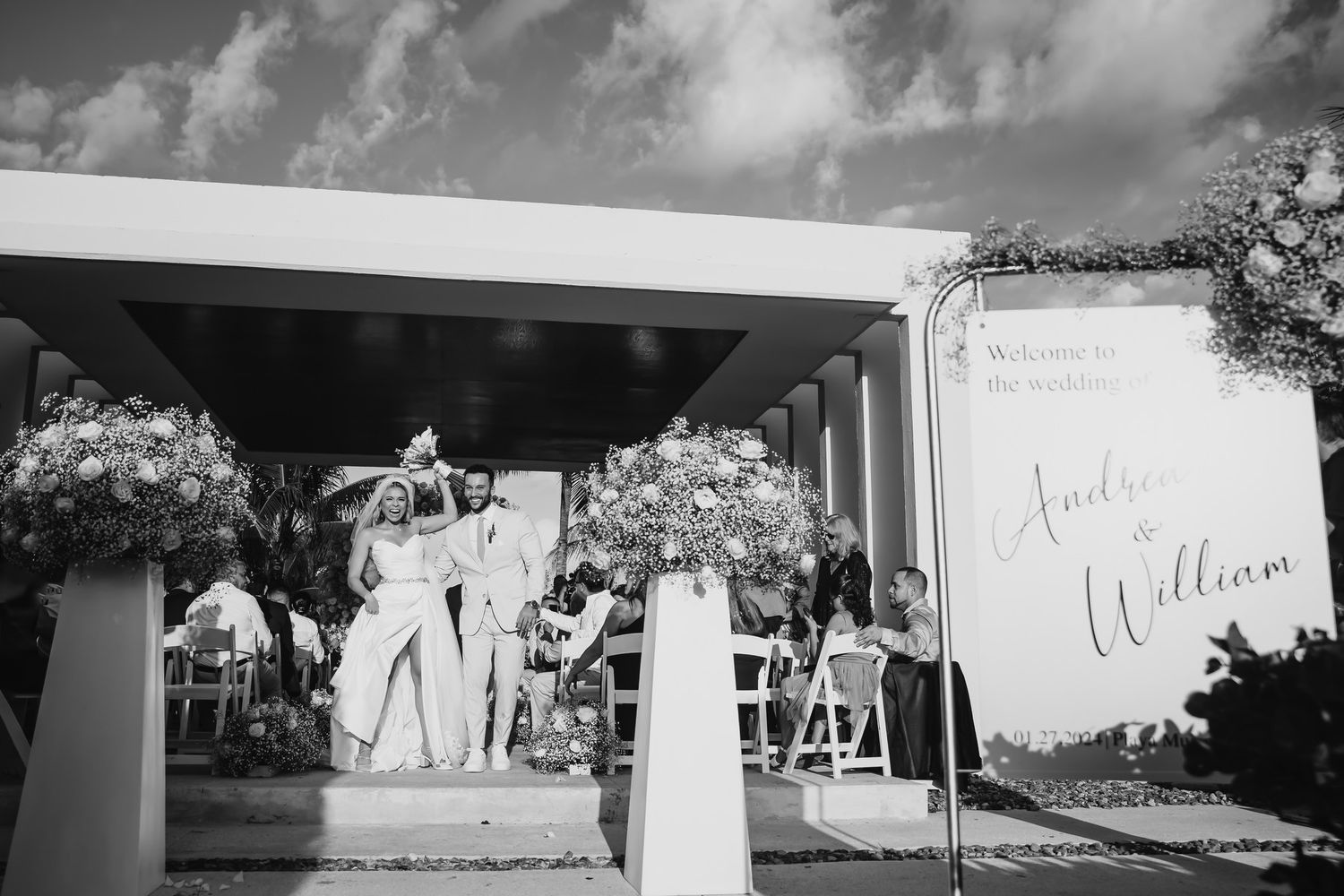 Black and white wedding reception photo with Andrea and William welcome sign and floral arrangements.