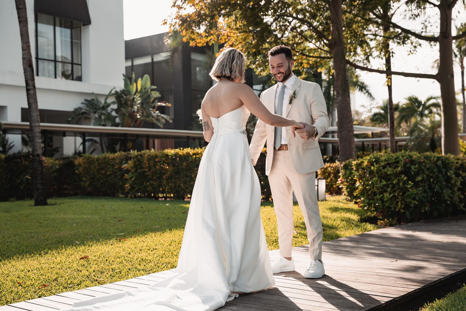Newlyweds sharing first look moment on sunny outdoor walkway.
