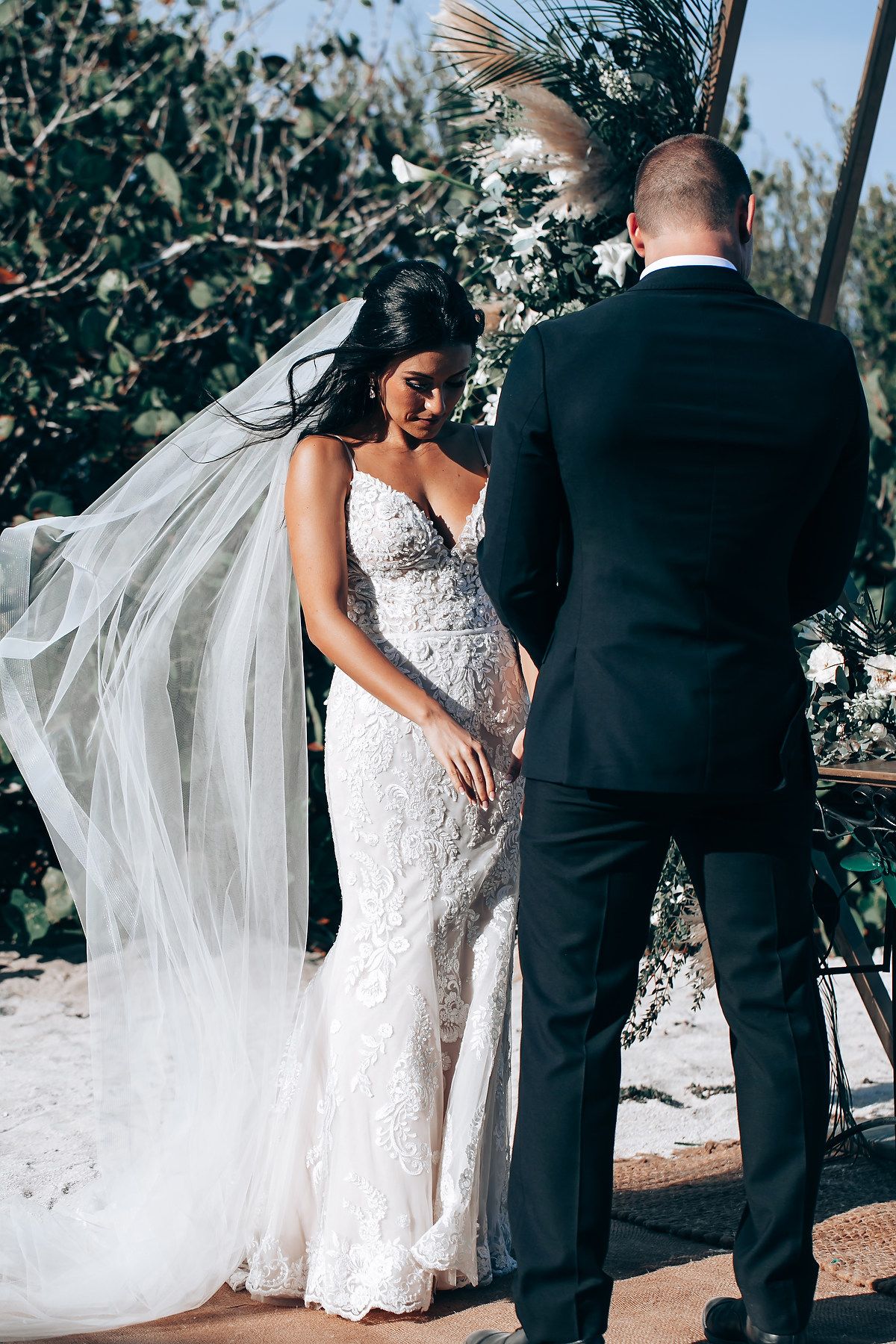 Elegant lace wedding dress with flowing train captured during intimate outdoor ceremony moments.