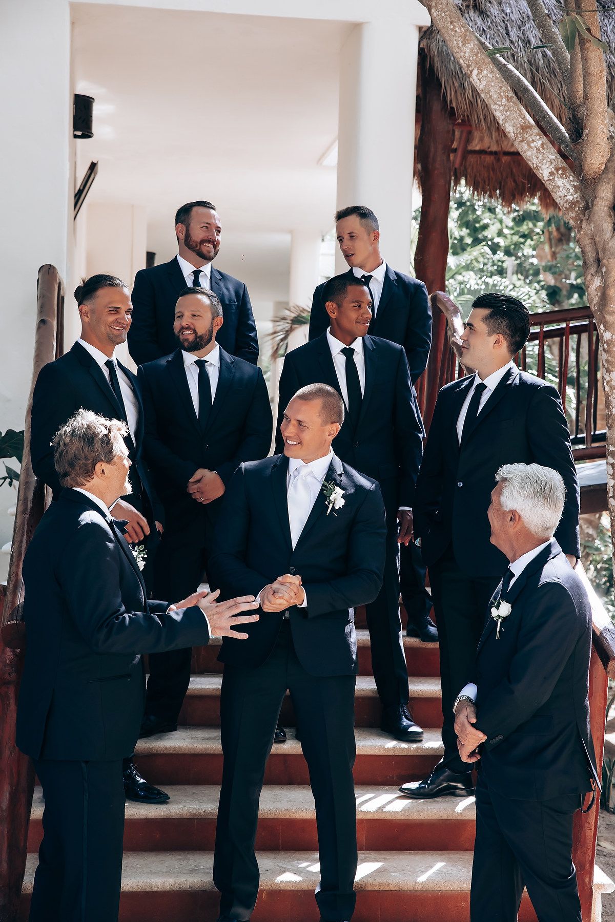 Wedding party members in formal attire share candid moments in an elegant indoor venue.