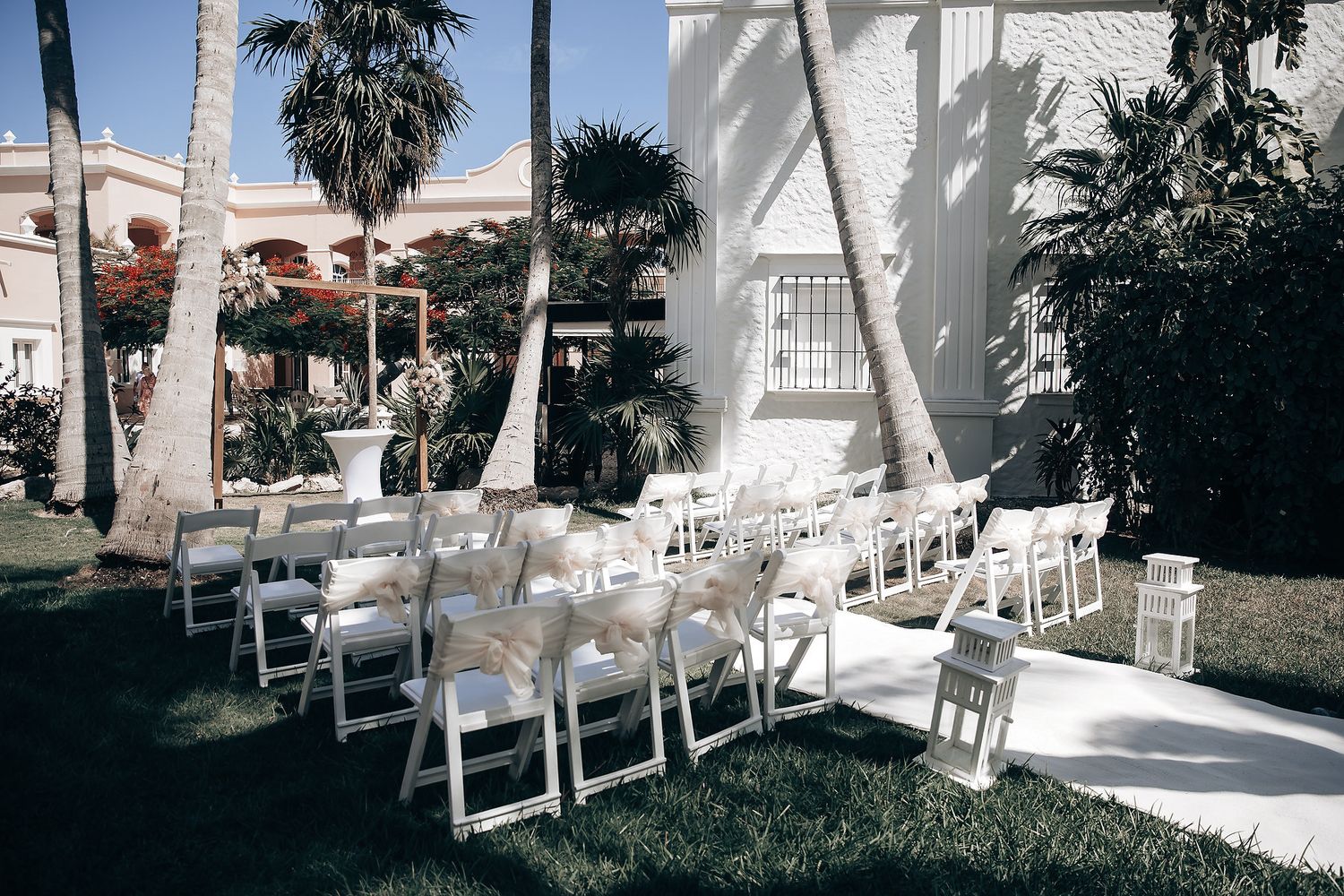 A wedding ceremony set up with rows of white chairs on a grassy outdoor patio.