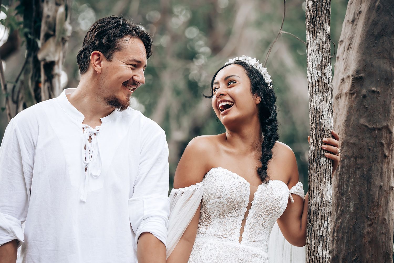 A couple shares a joyful moment together while posing in a natural forest setting.