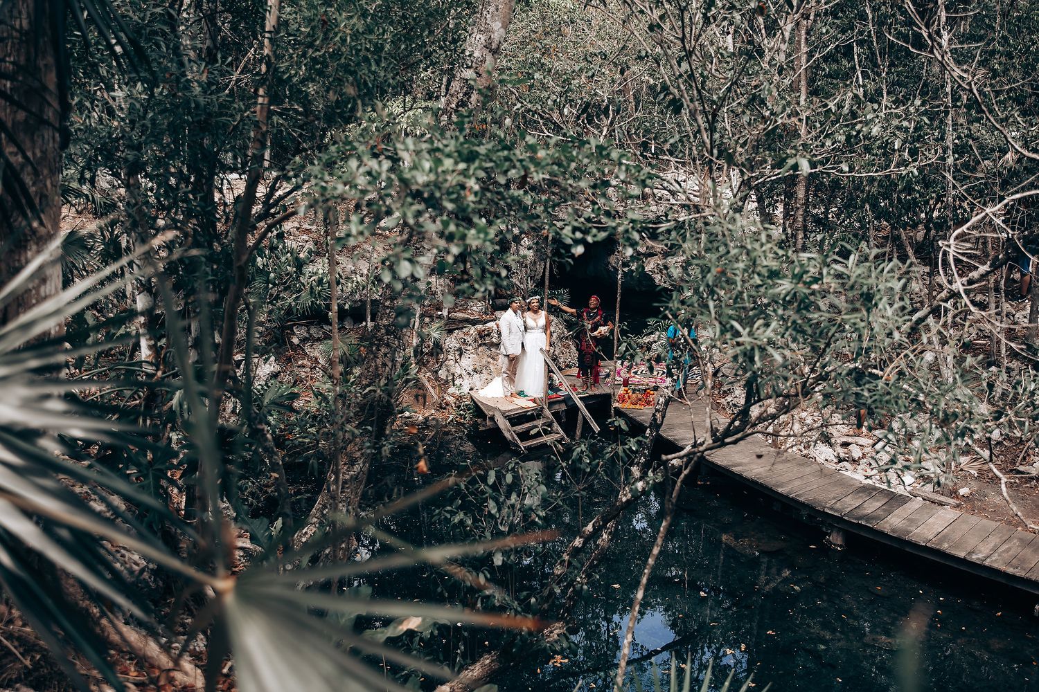 Natural cave wedding venue decorated with hanging lights and surrounded by lush forest vegetation.