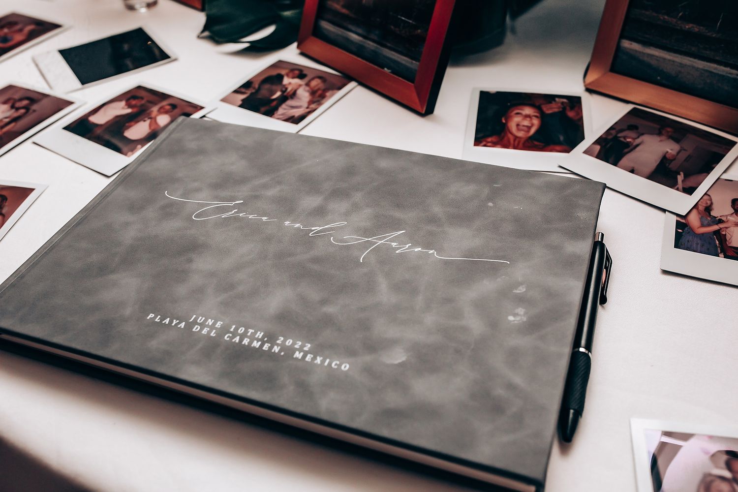 Wedding photo album and prints laid out on dark surface with elegant grey covers.