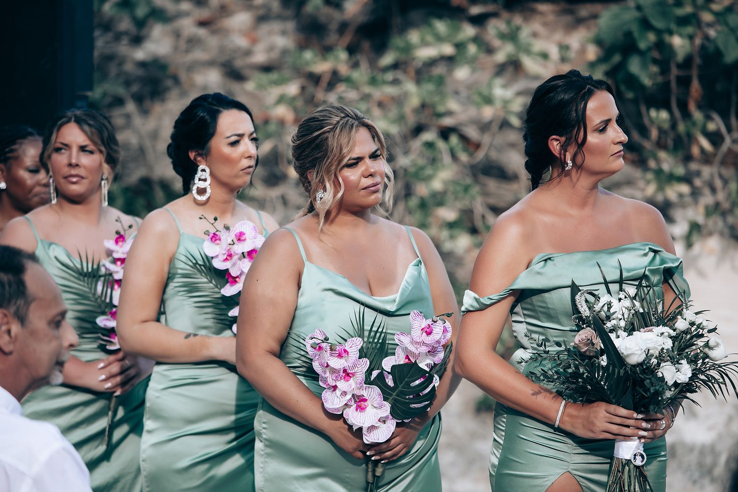 Bridesmaids in sage green dresses holding pink and white bouquets.