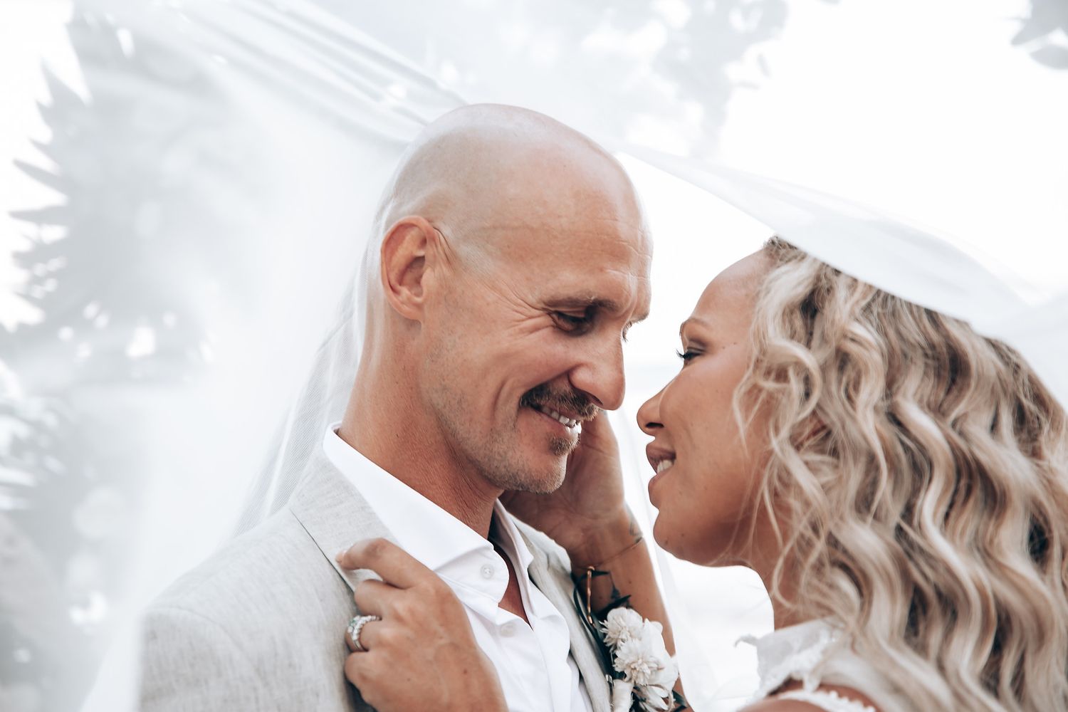 Romantic beach wedding portrait with floral arch backdrop.